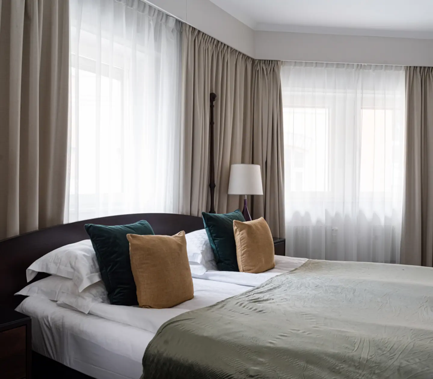 Bright hotel room with bed, desk and bedside lamp