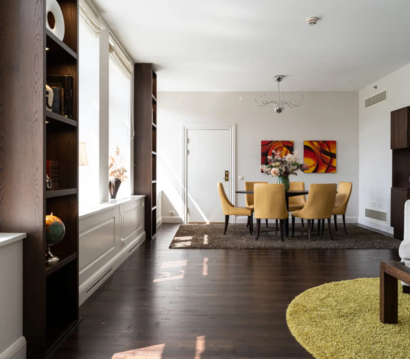 Modern dining room with yellow chairs around a round table.
