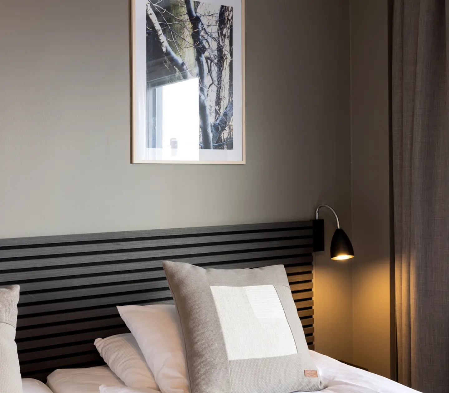 Close-up of black wooden headboard, pillow and bedside lamp