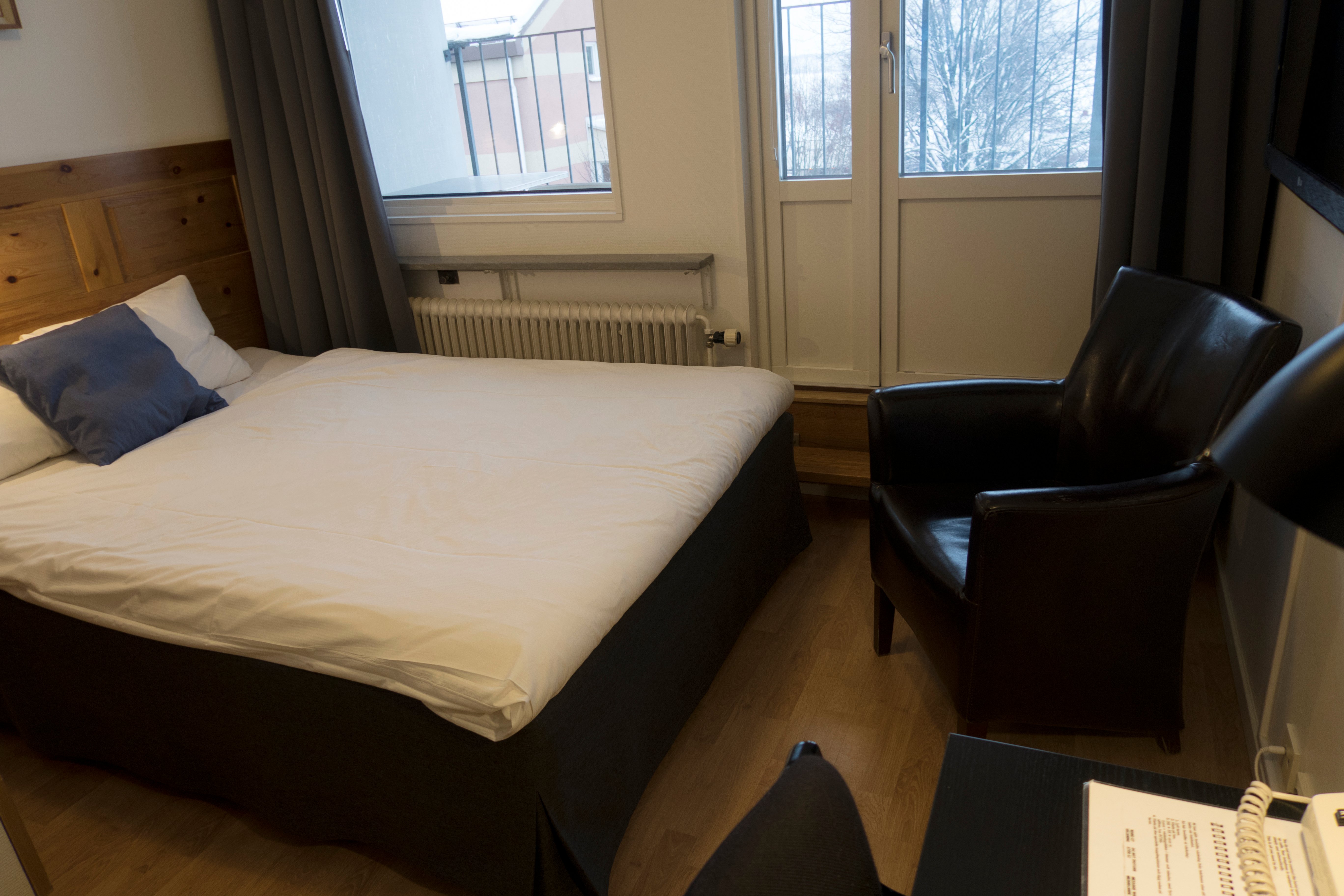 Hotellrum med sängar, svart läderfåtölj och balkong