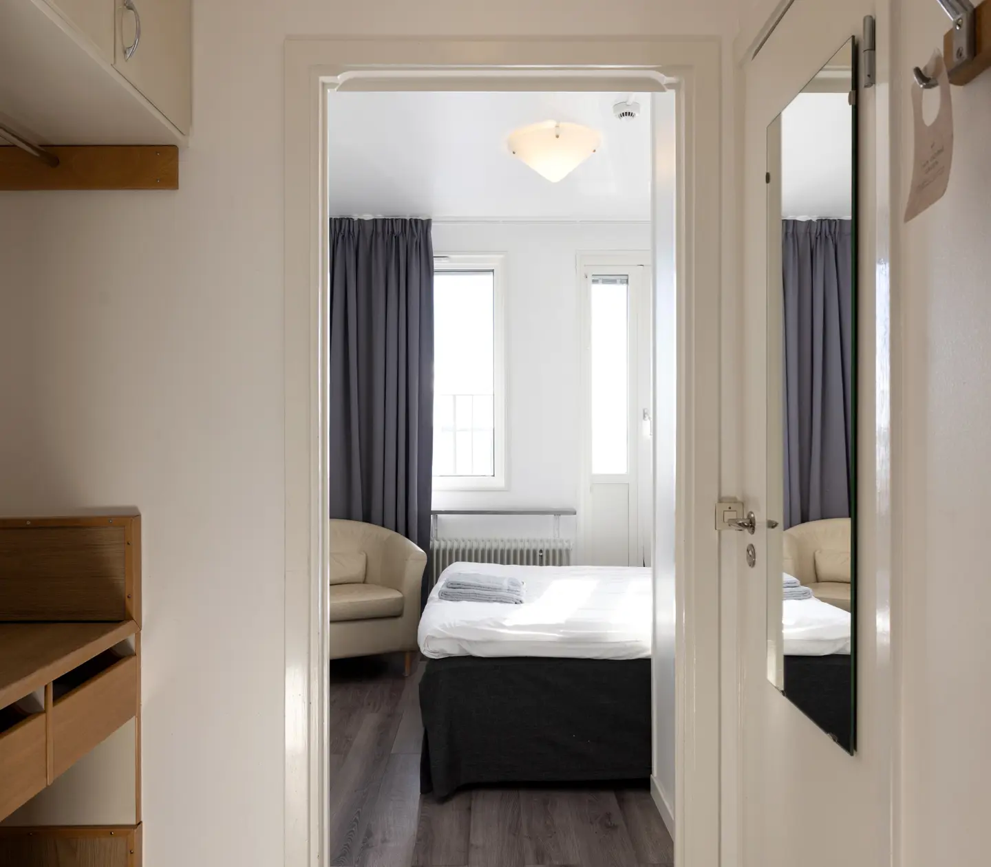Hotel room with bed, beige leather armchair and mirror