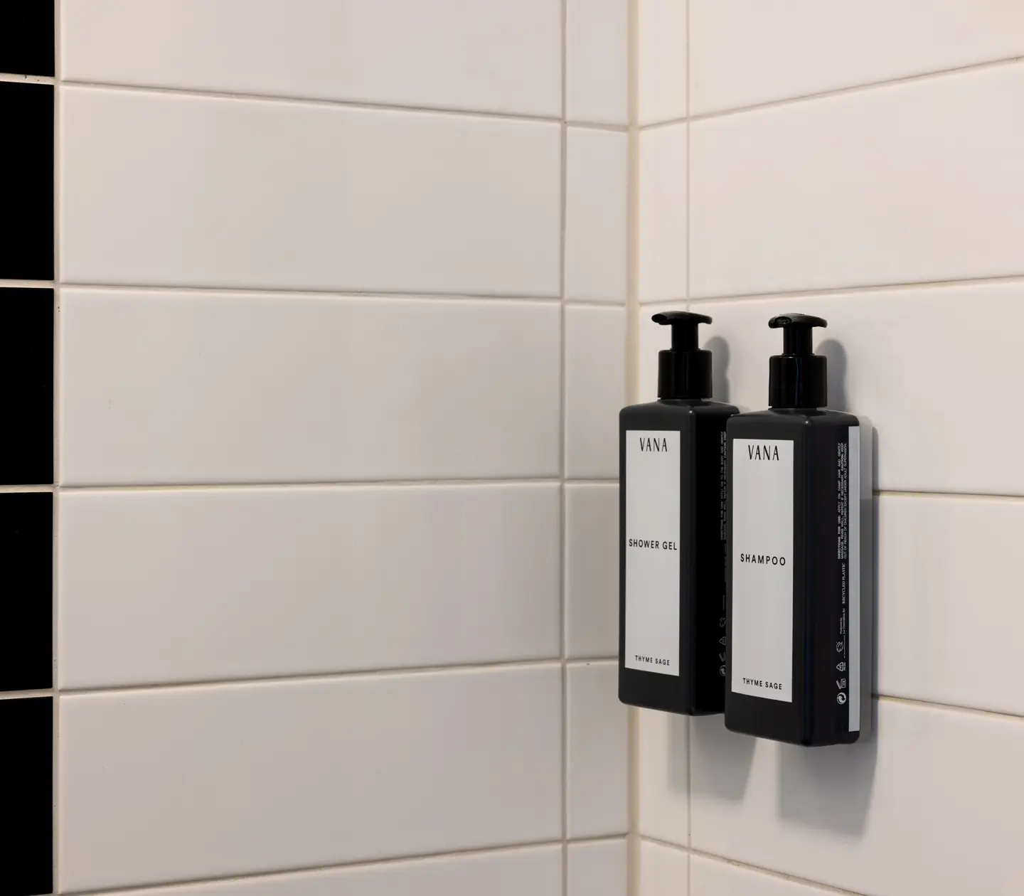Bathroom with black and white tiles and close-up of Shampoo and Shower Gel from Vana