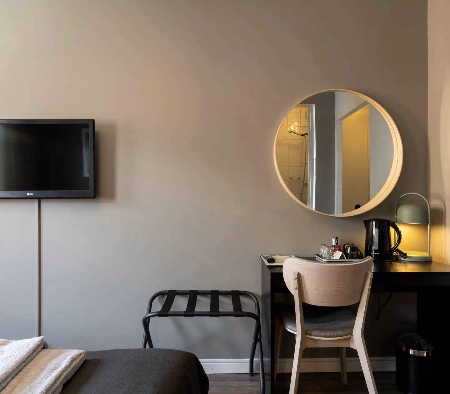 Hotel room with desk, round mirror and TV