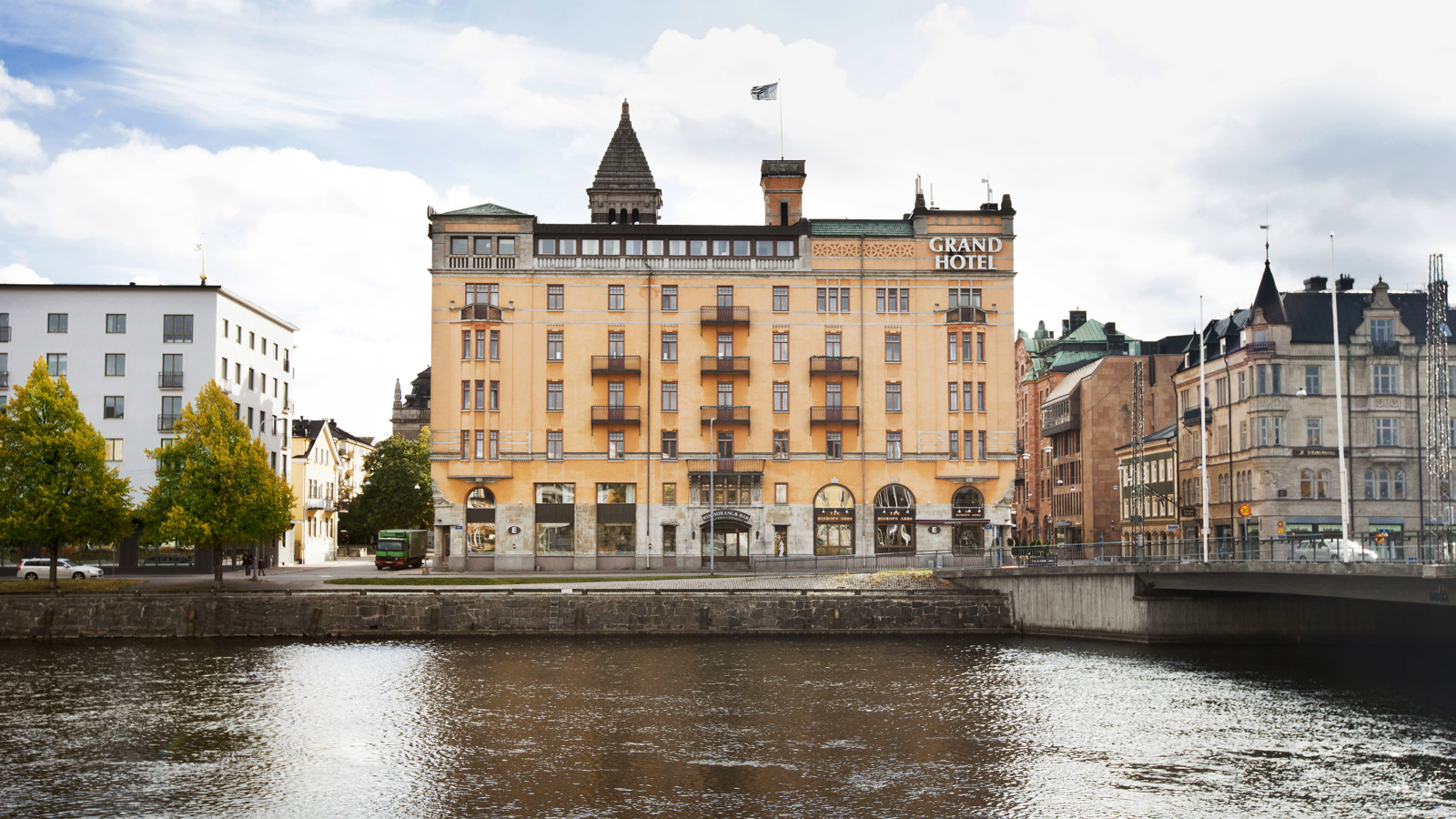 Orange fasaden av Elite Grand Hotel i Norrköping med Motala Ström framför