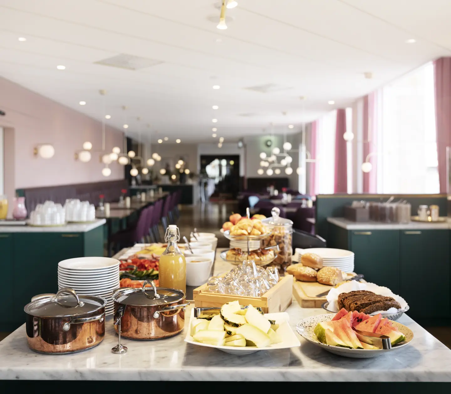 Breakfast buffet laid out on a table with dining areas in the background