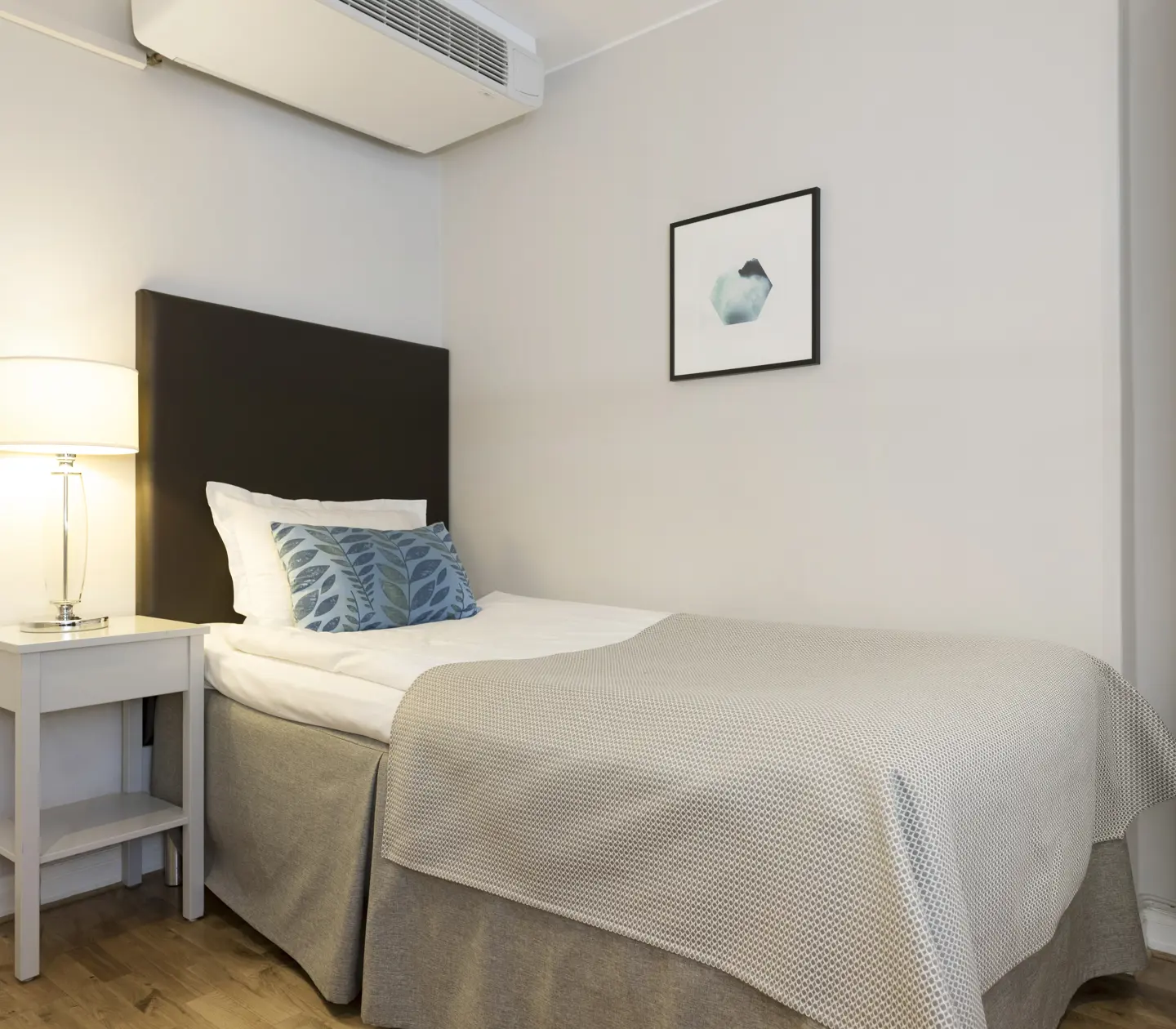Bright hotel room with bed, bedside table and bedside lamp