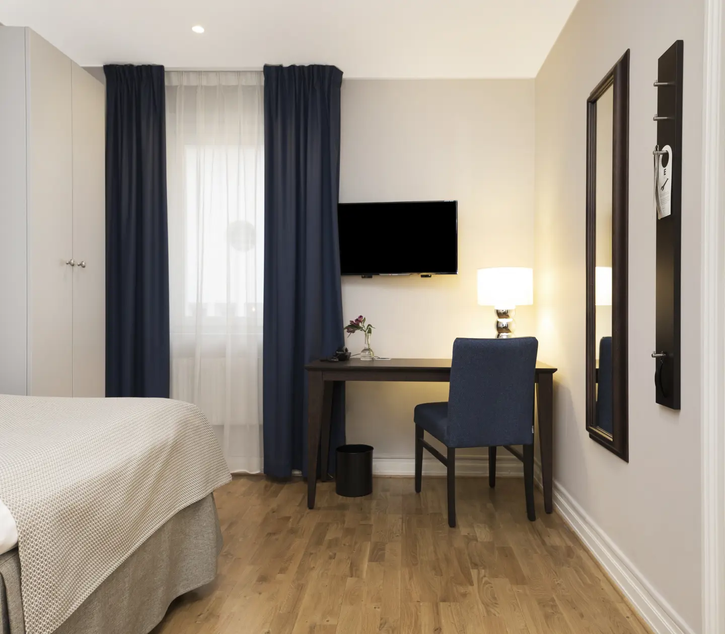 Bright hotel room with bed, wardrobe and desk