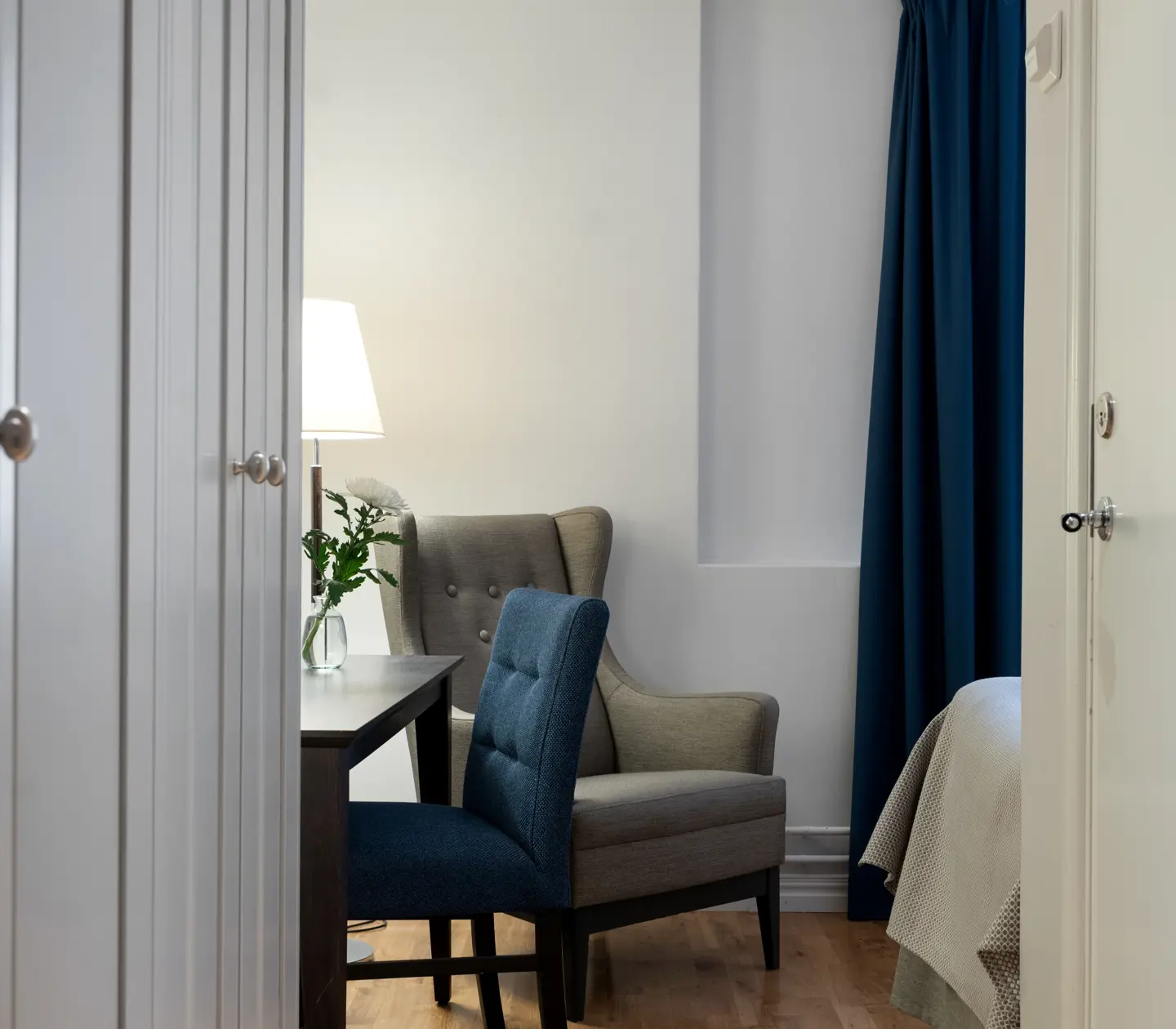 Bright hotel room with armchair, desk and wardrobe