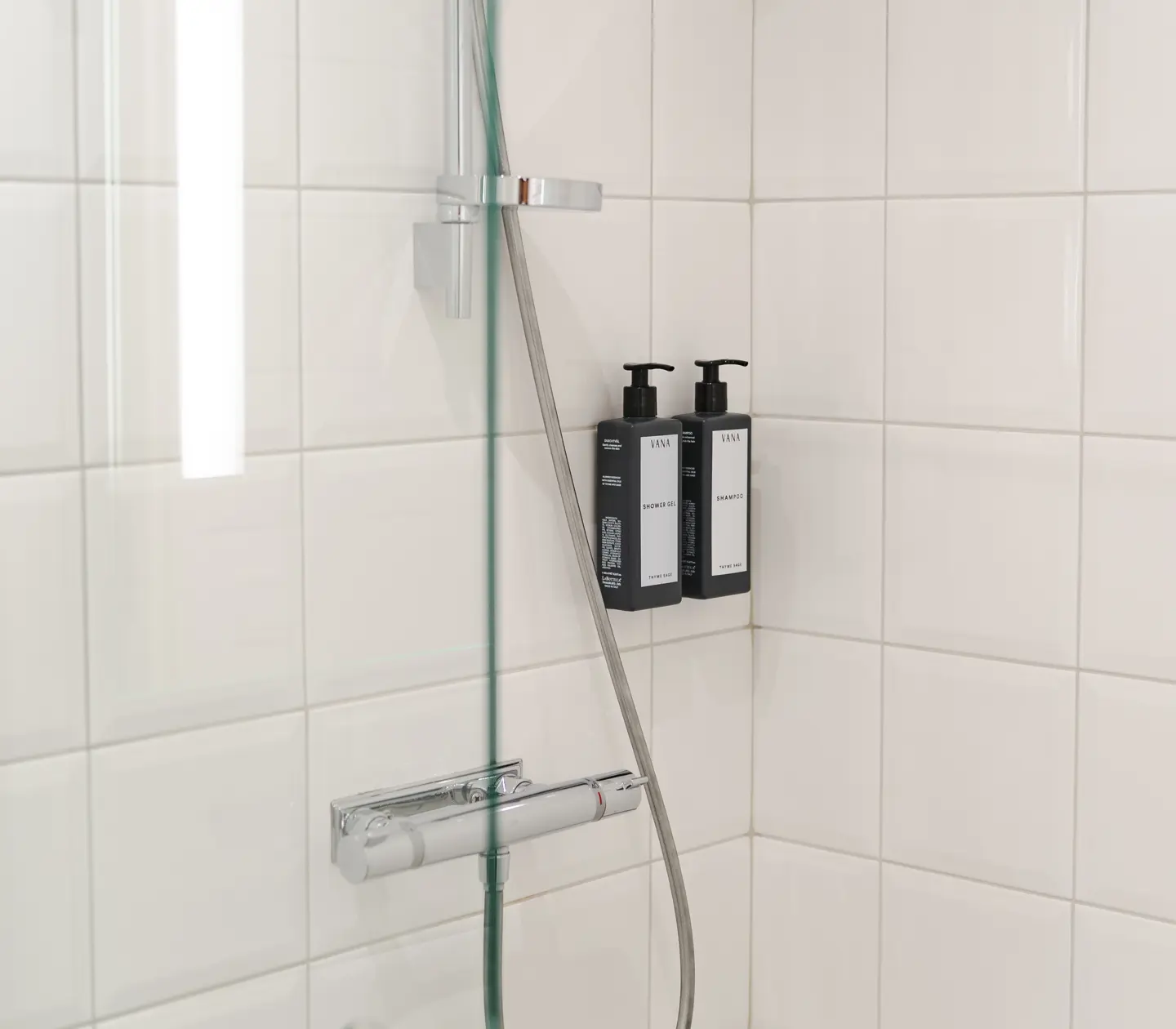Bright tiled bathroom with shower and shower gel