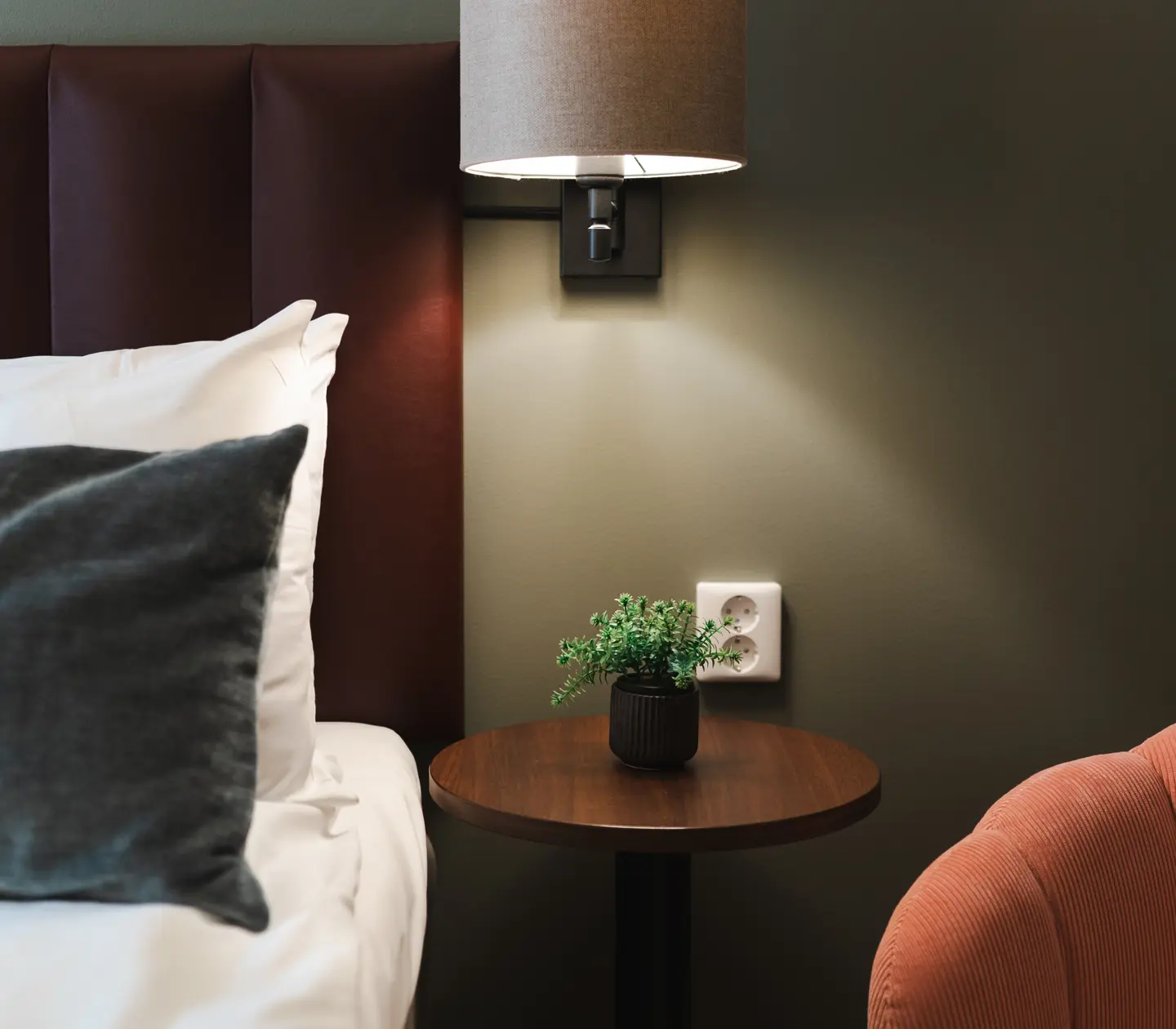 Close-up of hotel room with bed, bedside lamp and flower