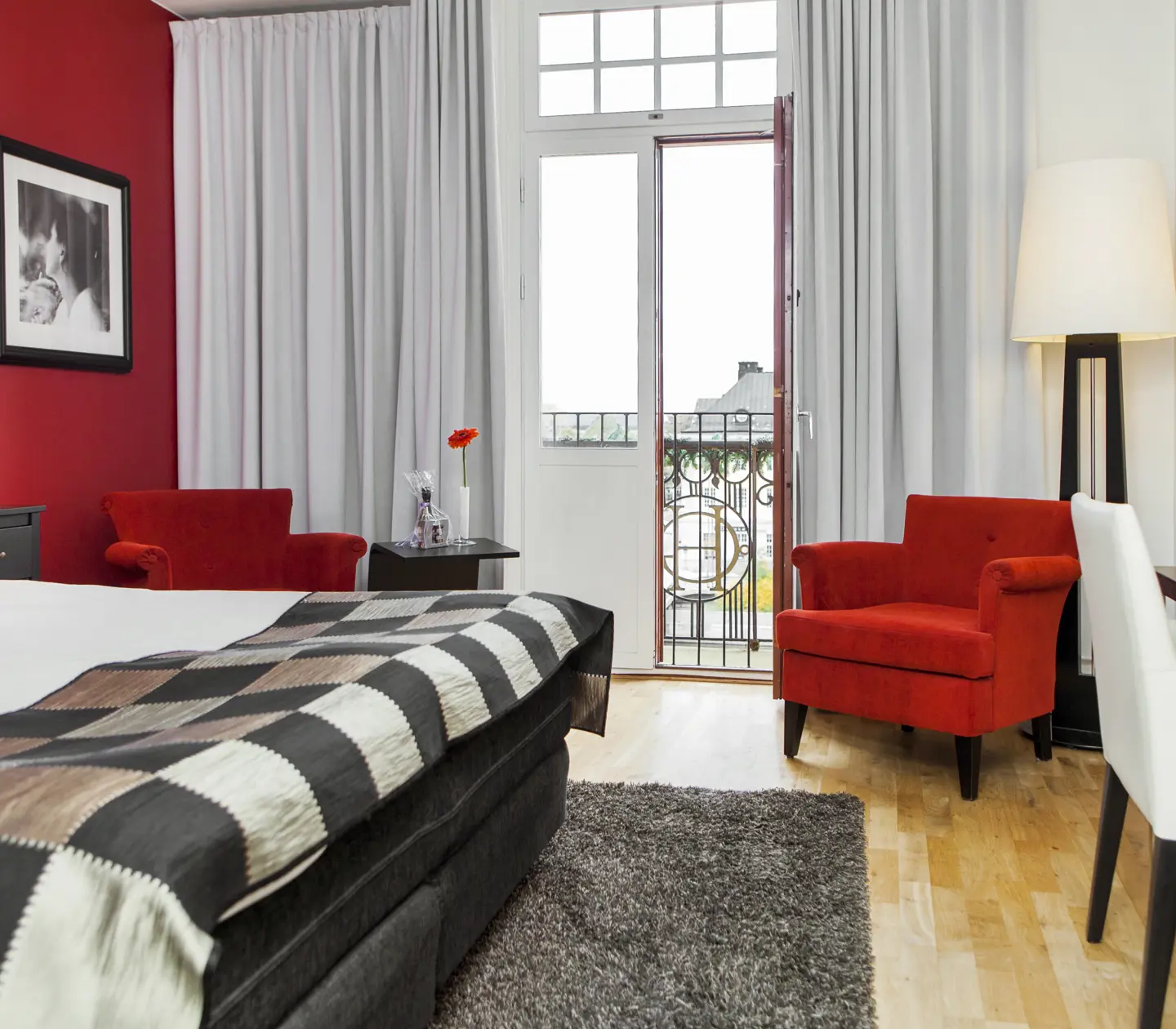 Hotel room with red wall, bed and red armchairs