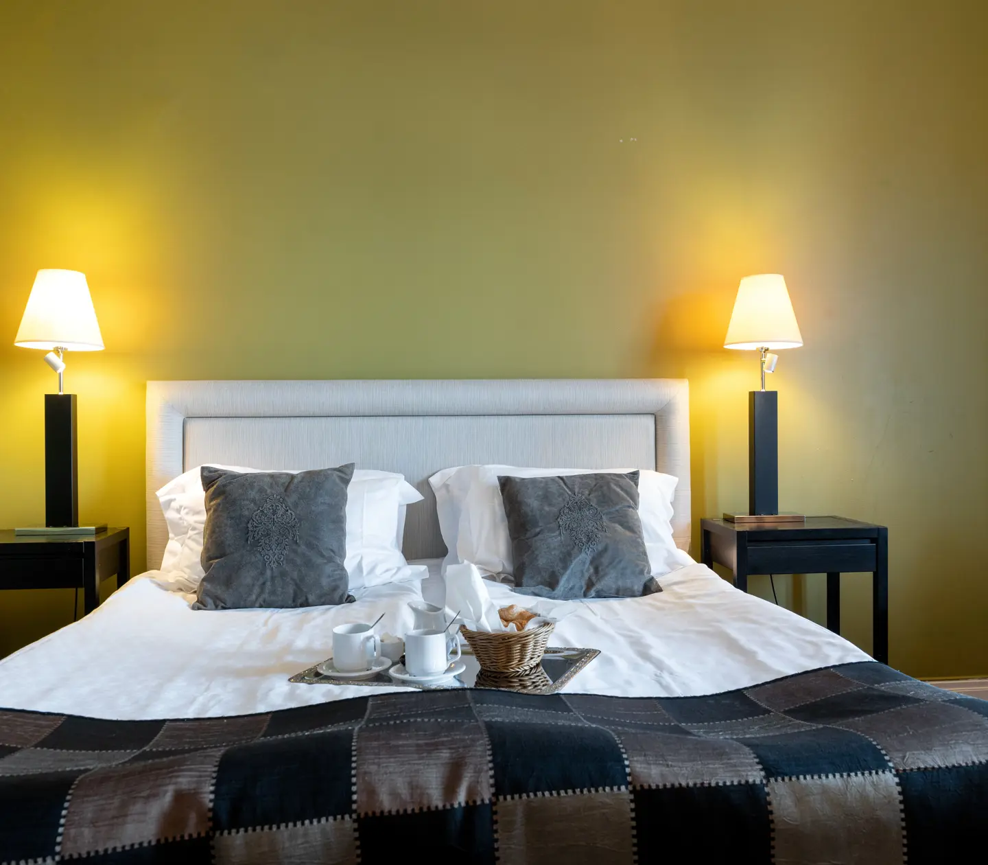 Hotel room with yellow wall, bed and breakfast tray on the bed