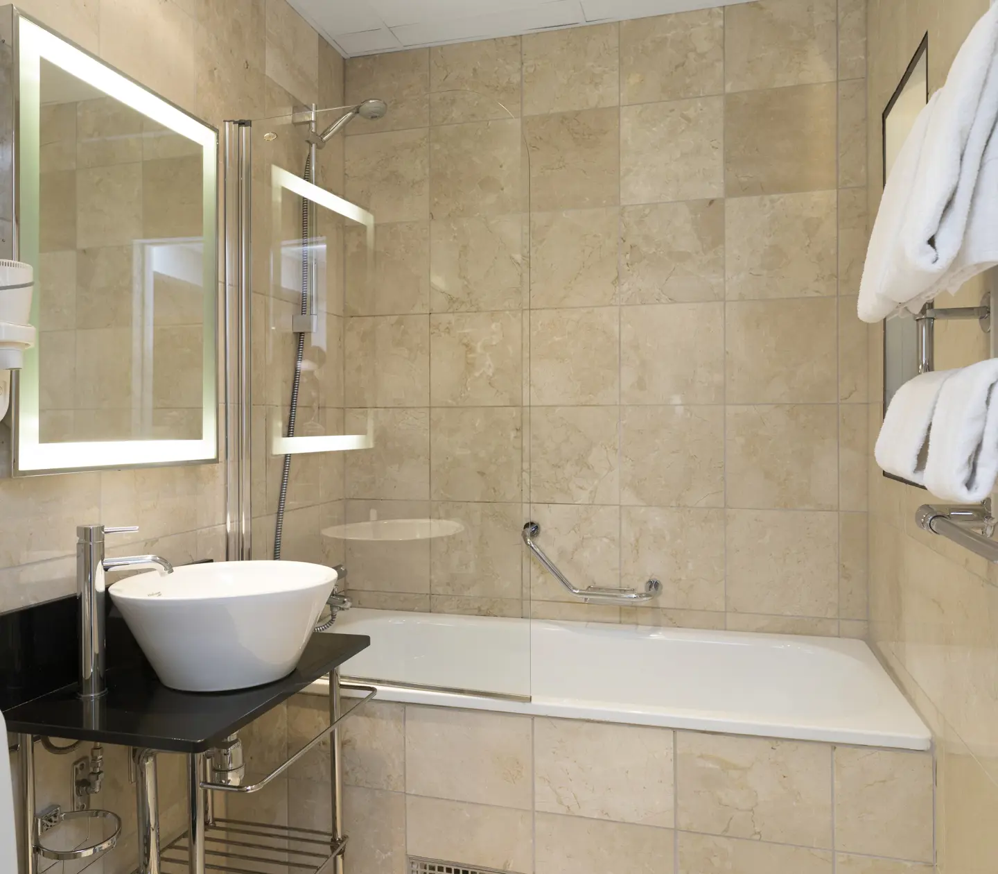 Beige bathroom with bathtub, sink and mirror