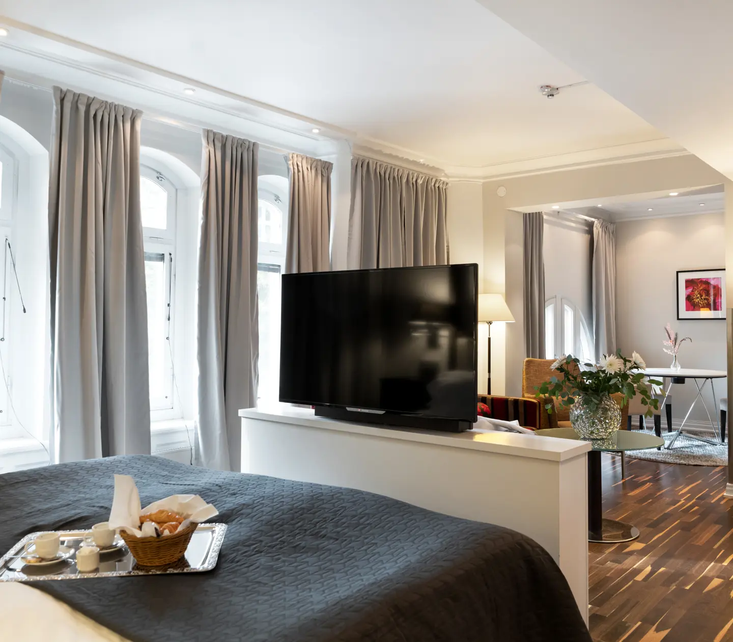 Hotel room with many windows, bouquet and breakfast tray on bed
