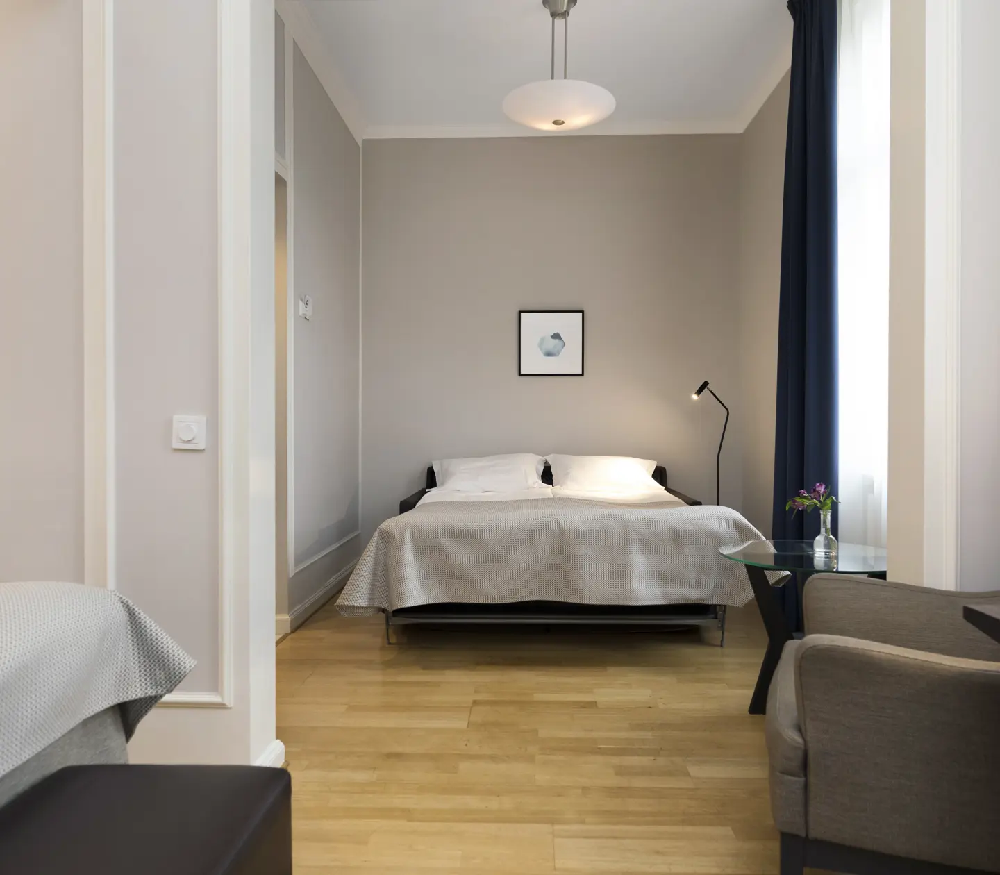 Bright hotel room with bed, armchair and painting