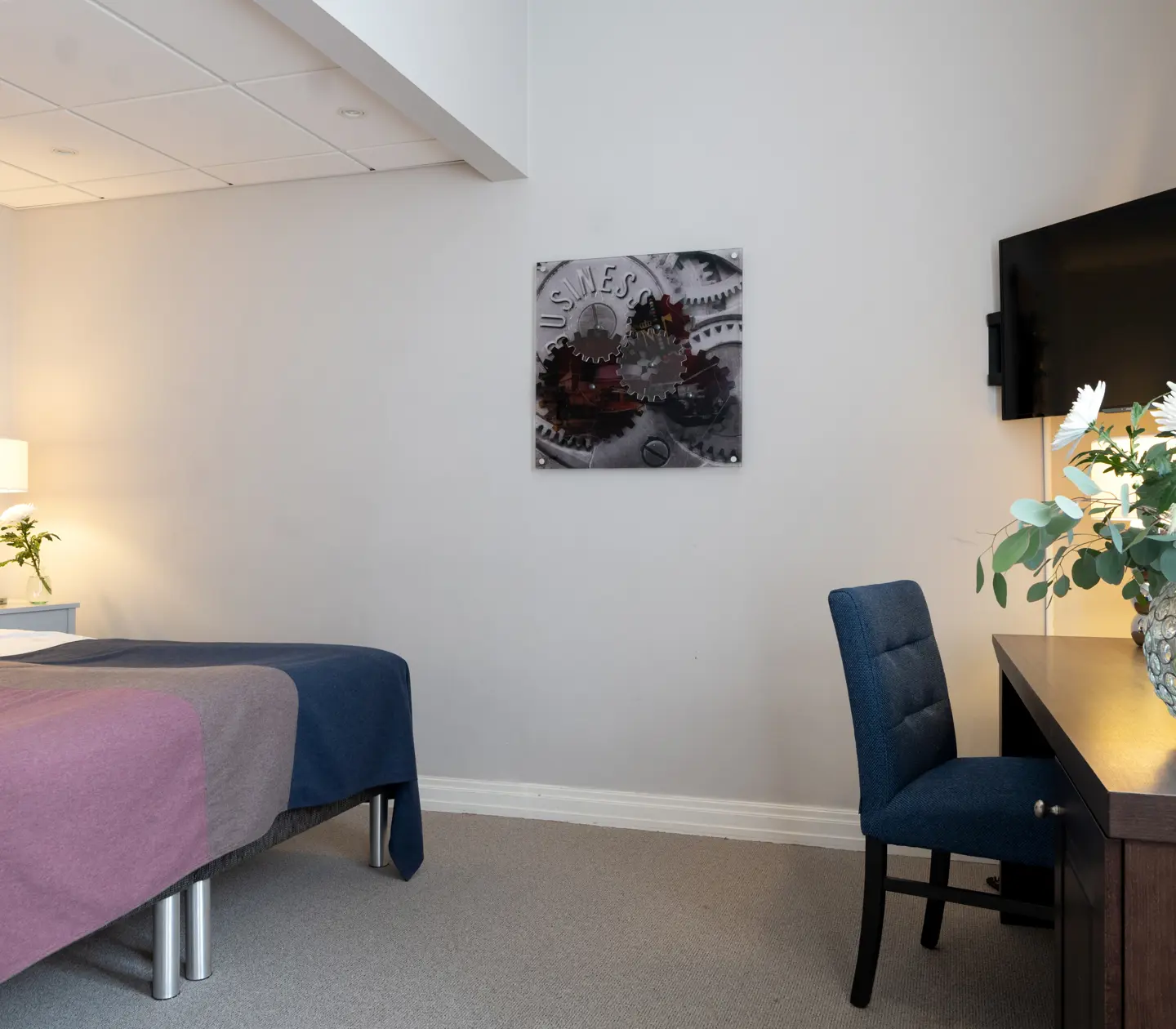 Bright hotel room with bed, desk and TV