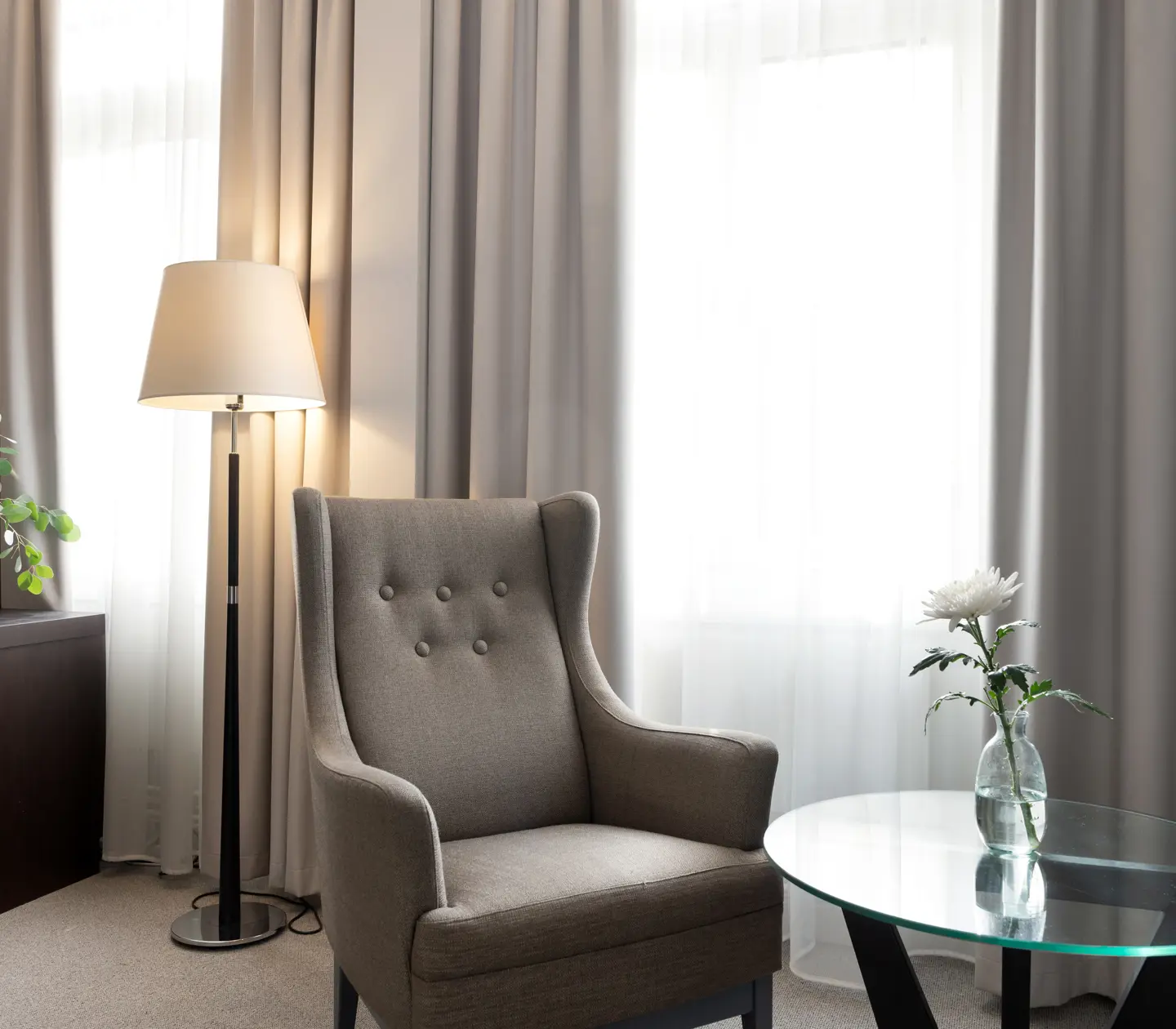 Bright hotel room with curtains, armchair and floor lamp