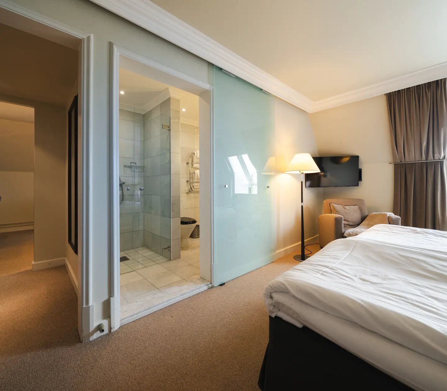 Suite with bed, armchair and door to bathroom