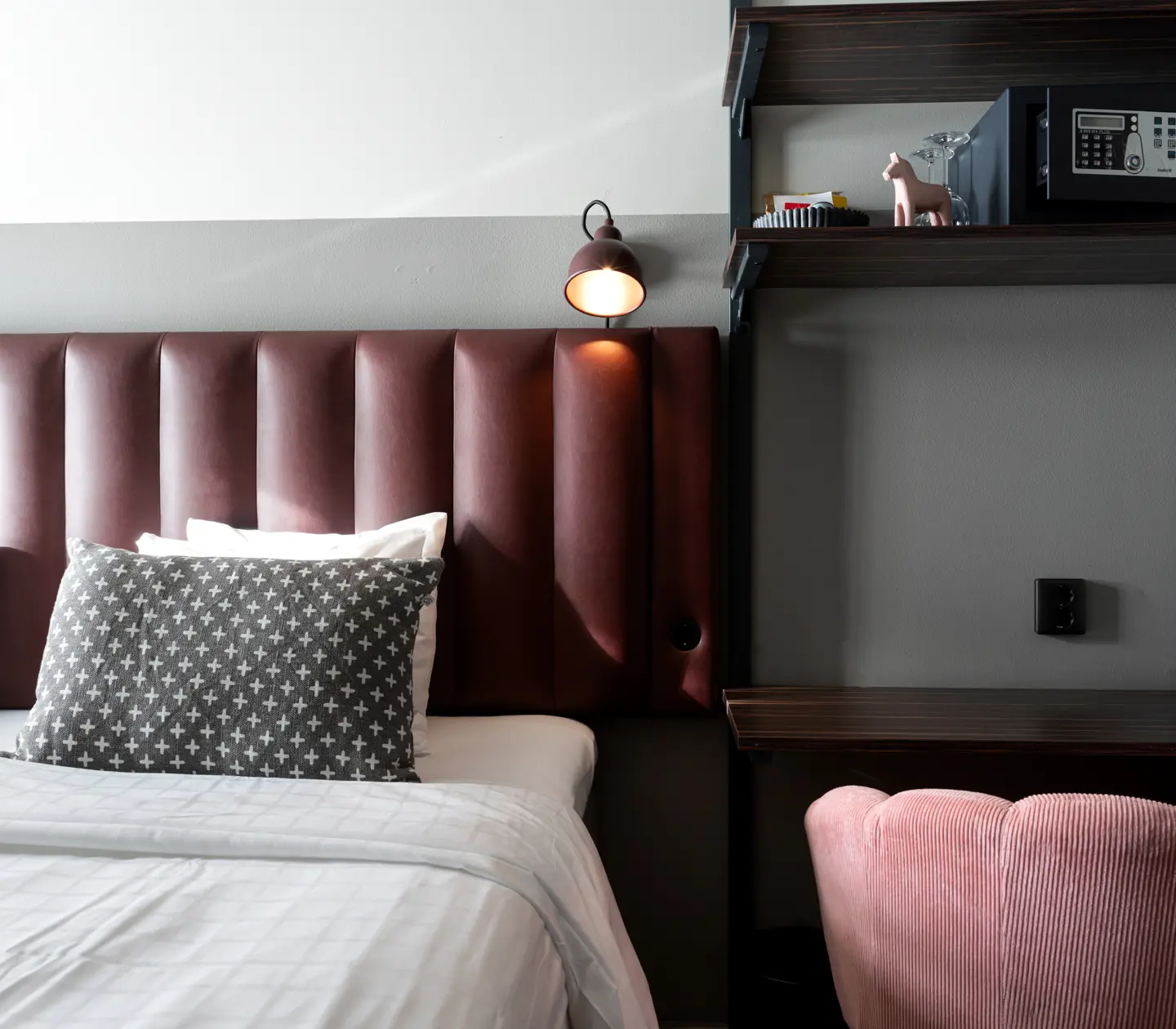 Close-up of bed, desk and pink armchair