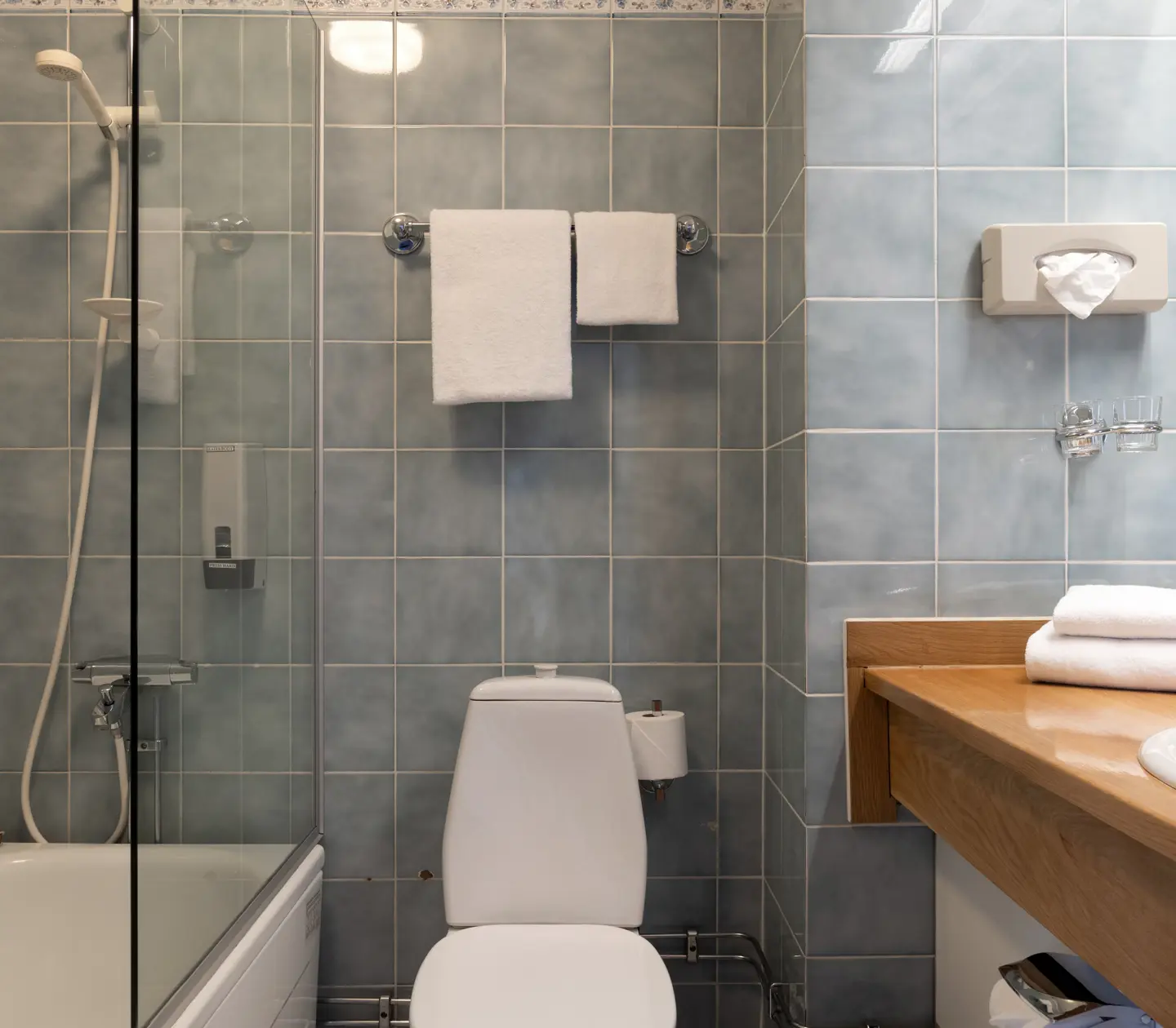 Blue tiled bathroom with bathroom, toilet and sink