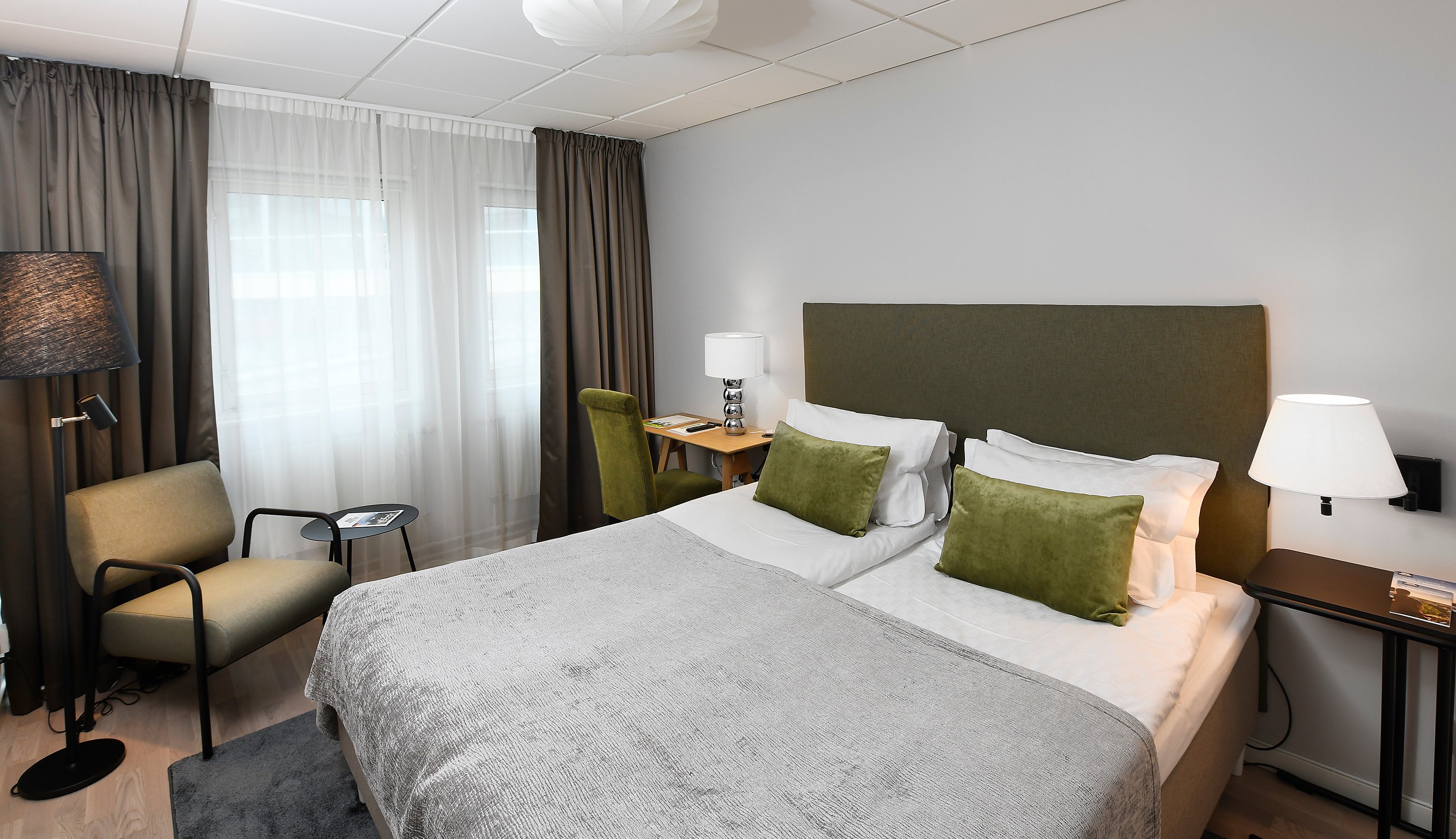 Bright hotel room with double bed, desk, armchair and window