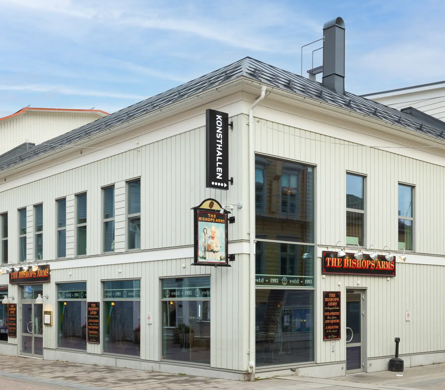 White facade of Hotel Bishops Arms with signs and large windows