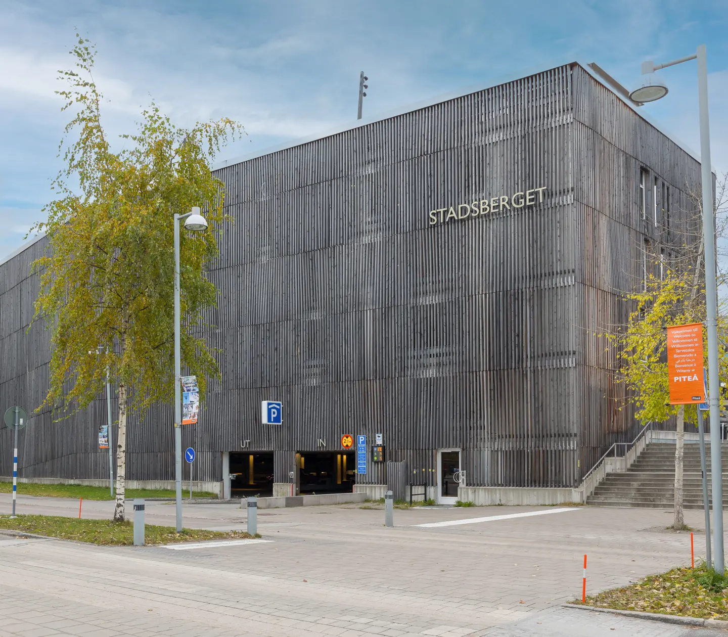 Gray parking garage with in and out signs and the "Stadsberget"