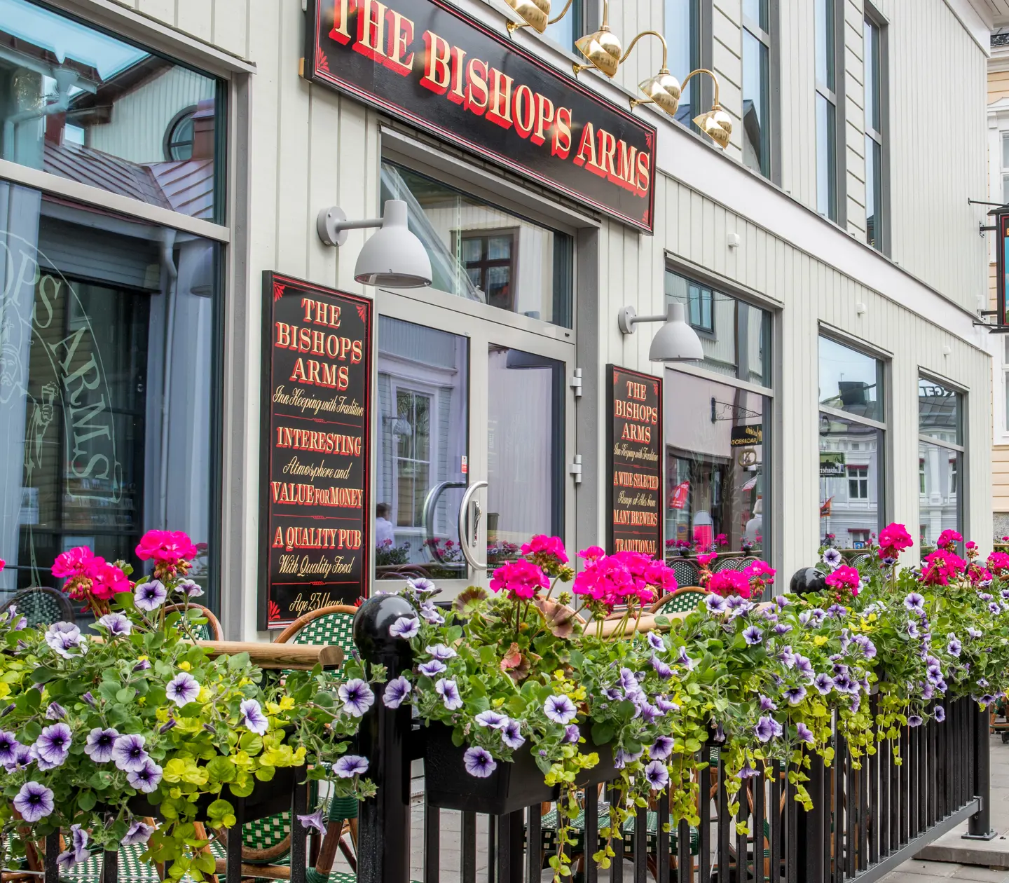 Outdoor seating for The Bishops Arms with flowers, signs and dining groups