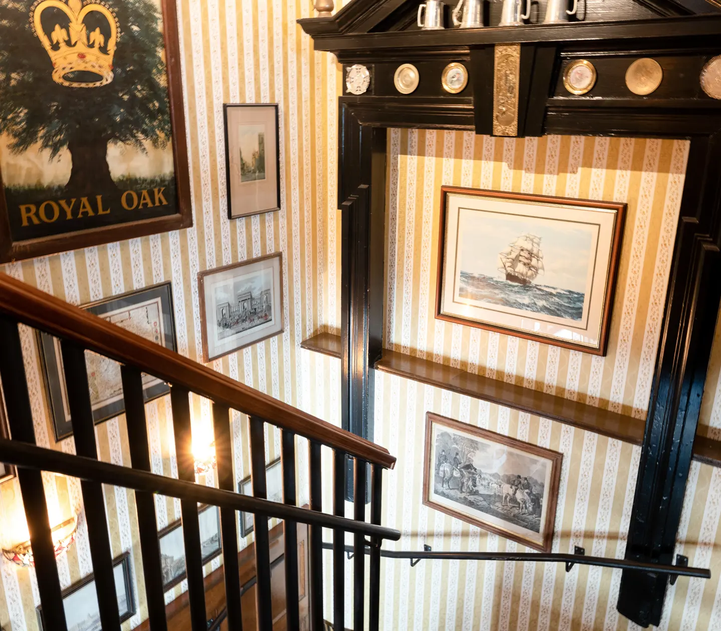Hotel environment with stairs, striped wallpaper and many paintings