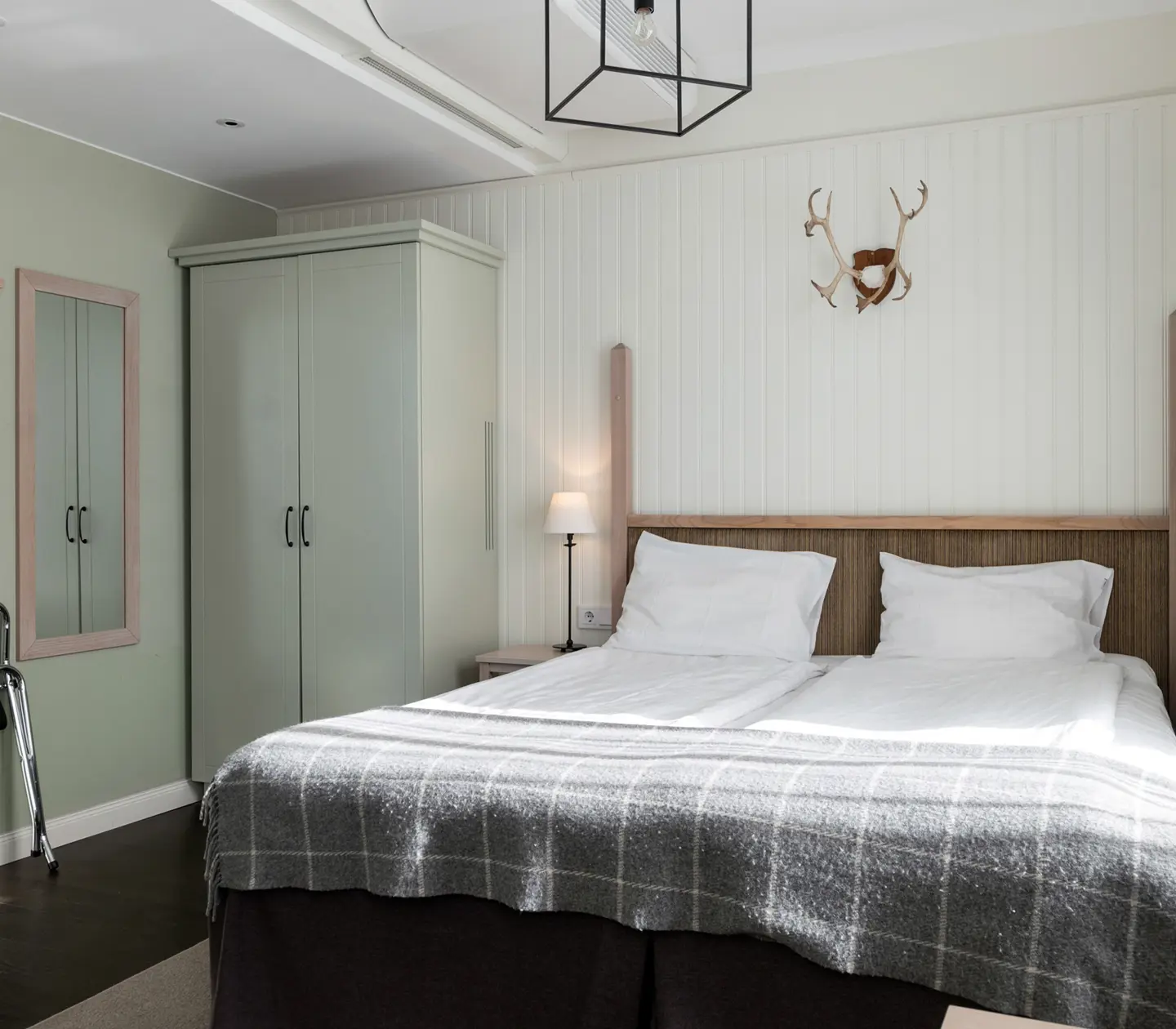 Cozy hotel room with bed, wardrobe and animal horns on the wall