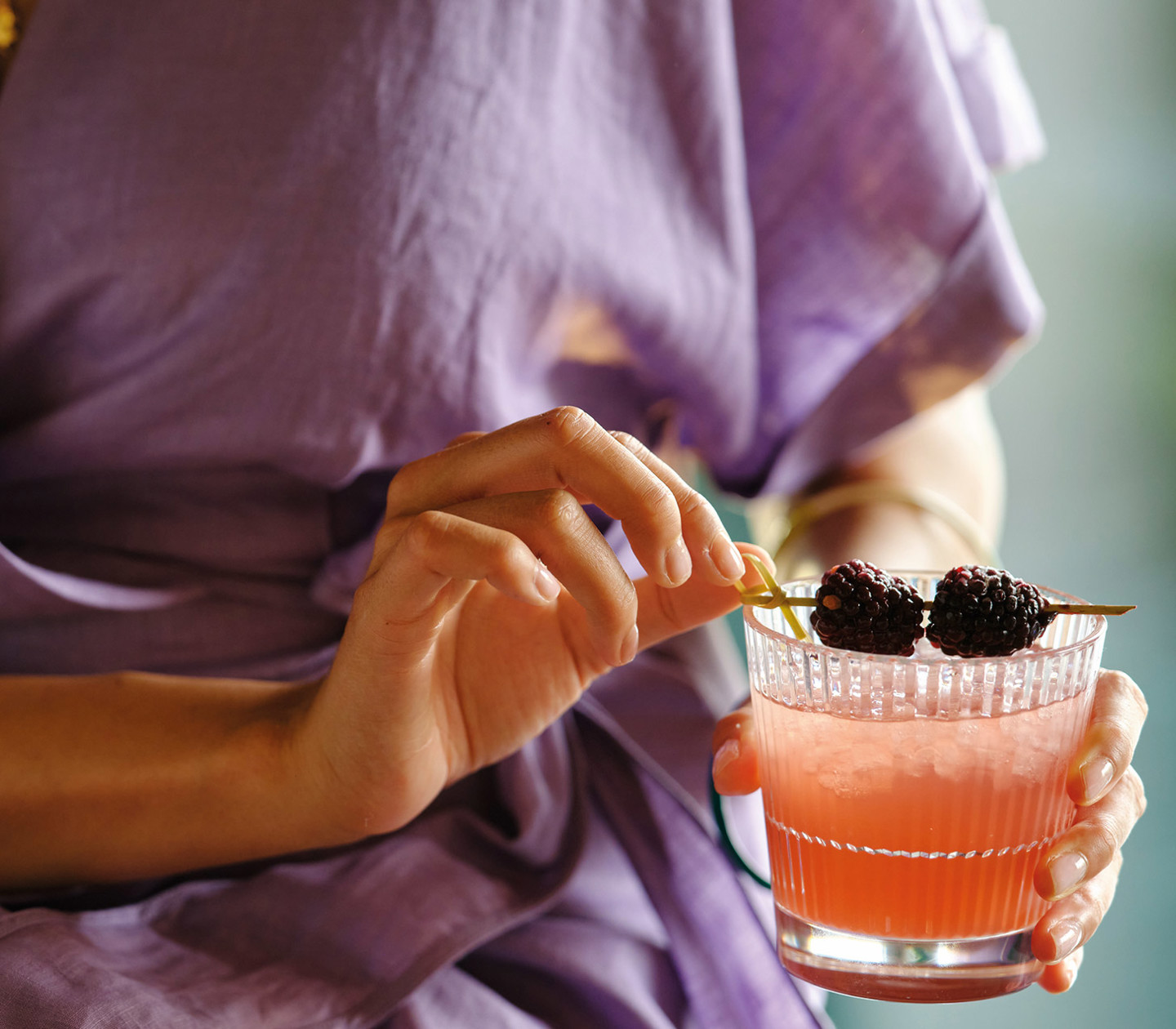 Kvinna i lila klänning med en drink i handen