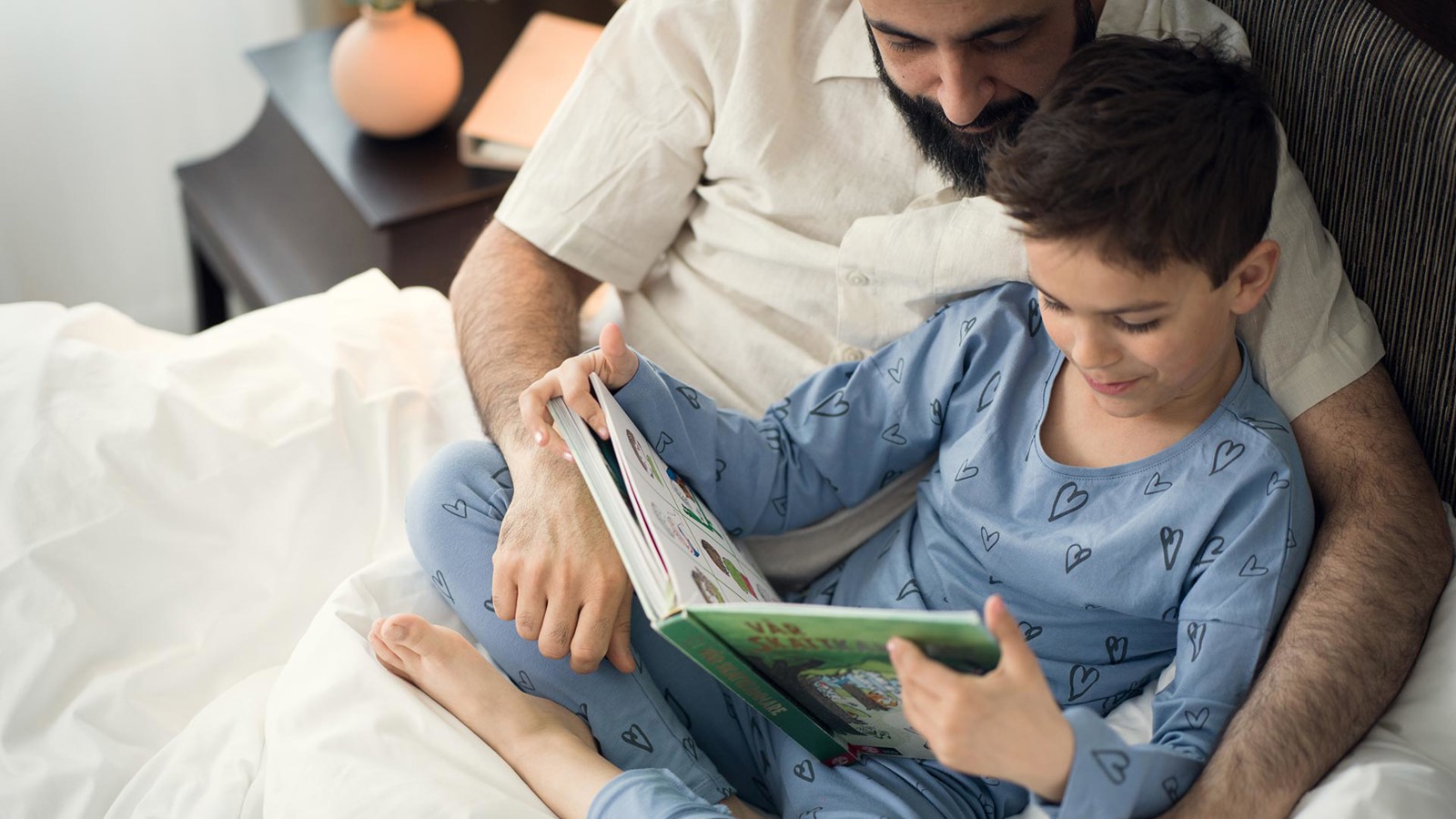Dad and son reading a book in bed 