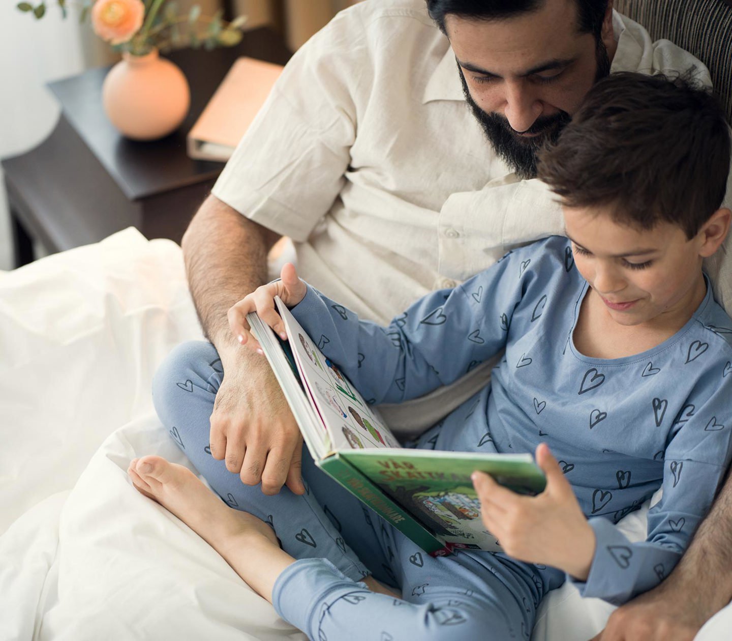 Pappa och son läser en bok i sängen