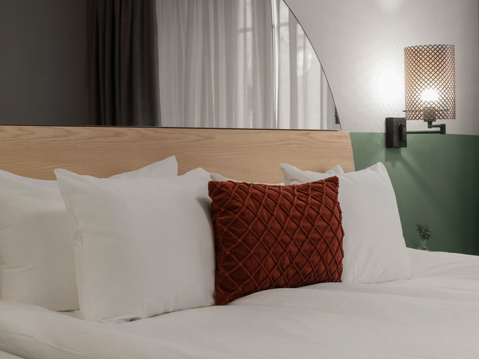 Mysigt hotellrum med säng, spegel och sänglampa