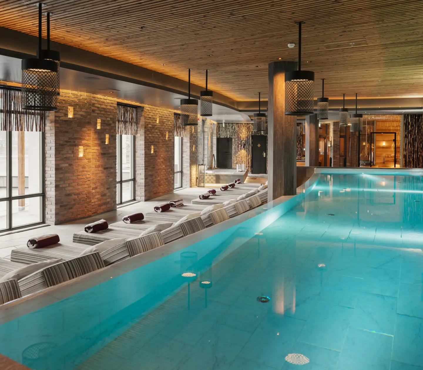 Spamiljö med stor pool, många solsängar och stora fönster