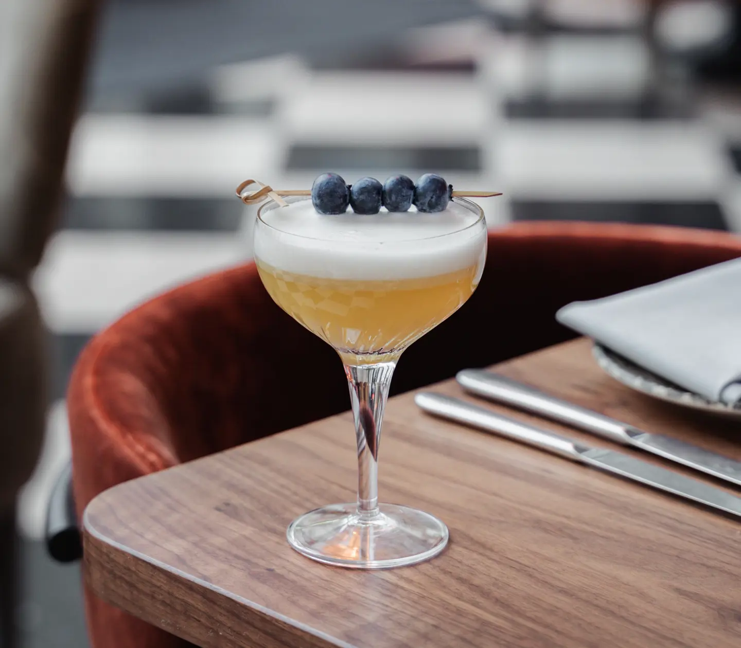 Gul drink serverad på bord med blåbär på pinne ovanpå glas