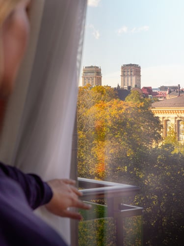 Kvinna som tittar ut från fönster och överblickar ett höstigt Stockholm