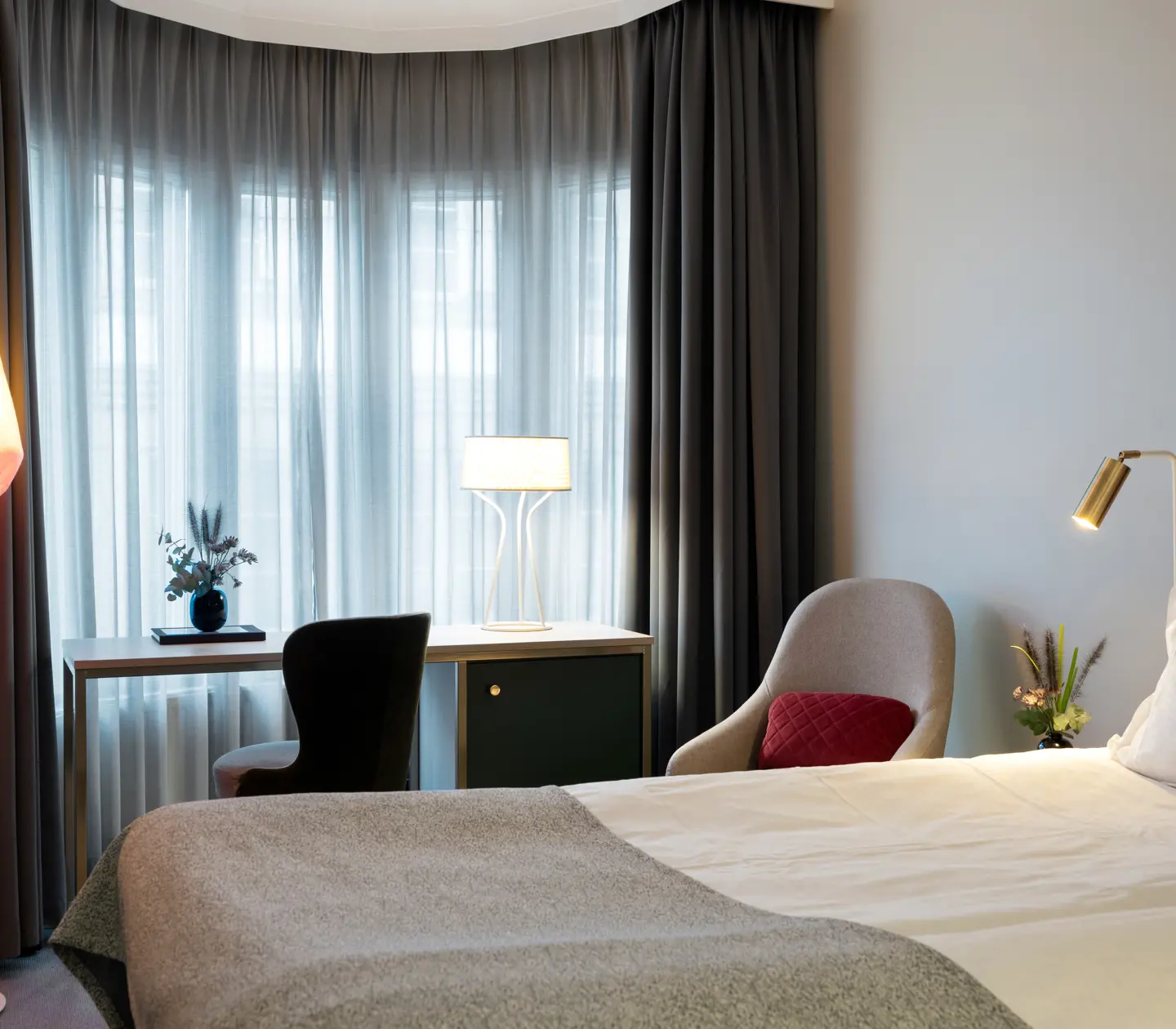 Double room with large window and bed, desk and armchair