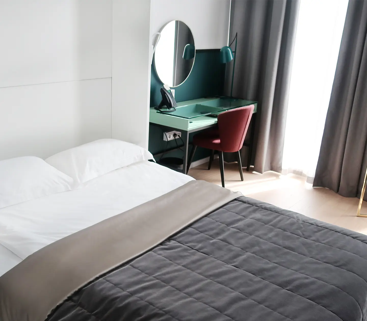 Bright hotel room with bed, desk and mirror