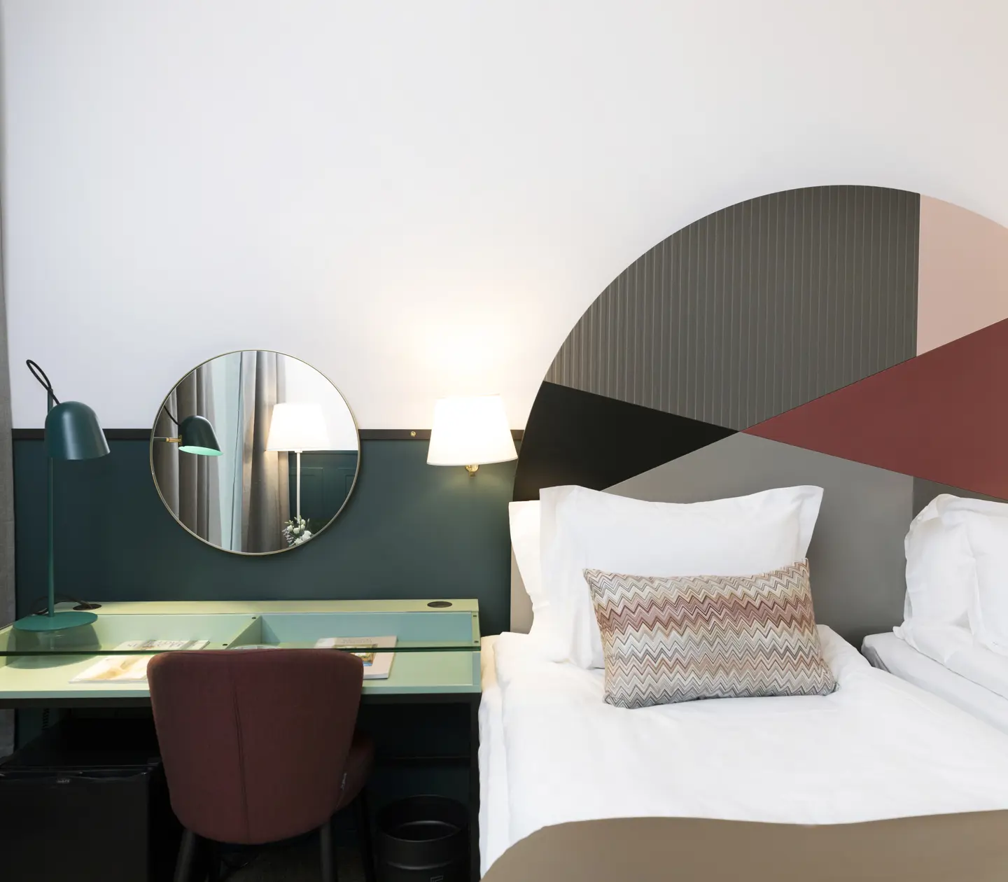 Bright hotel room with beds, colorful headboard and desk
