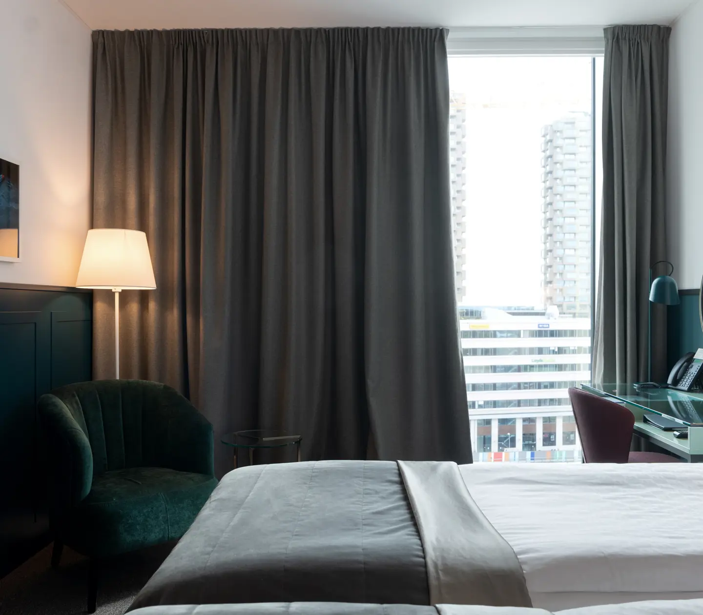 Bright hotel room with beds, desk and large window