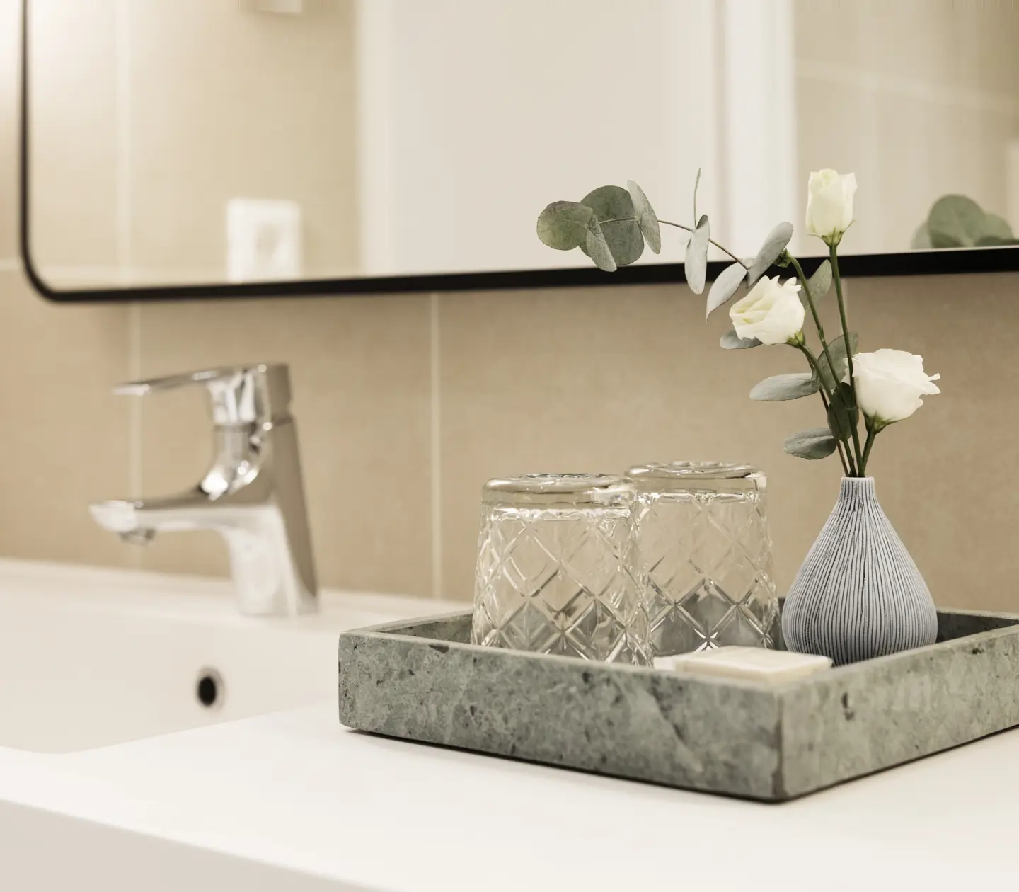 Beige bathroom with sink and marble tray with glass and flower