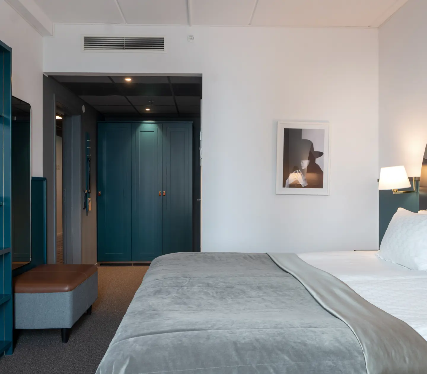 Bright hotel room with bed, wardrobe and bookshelf