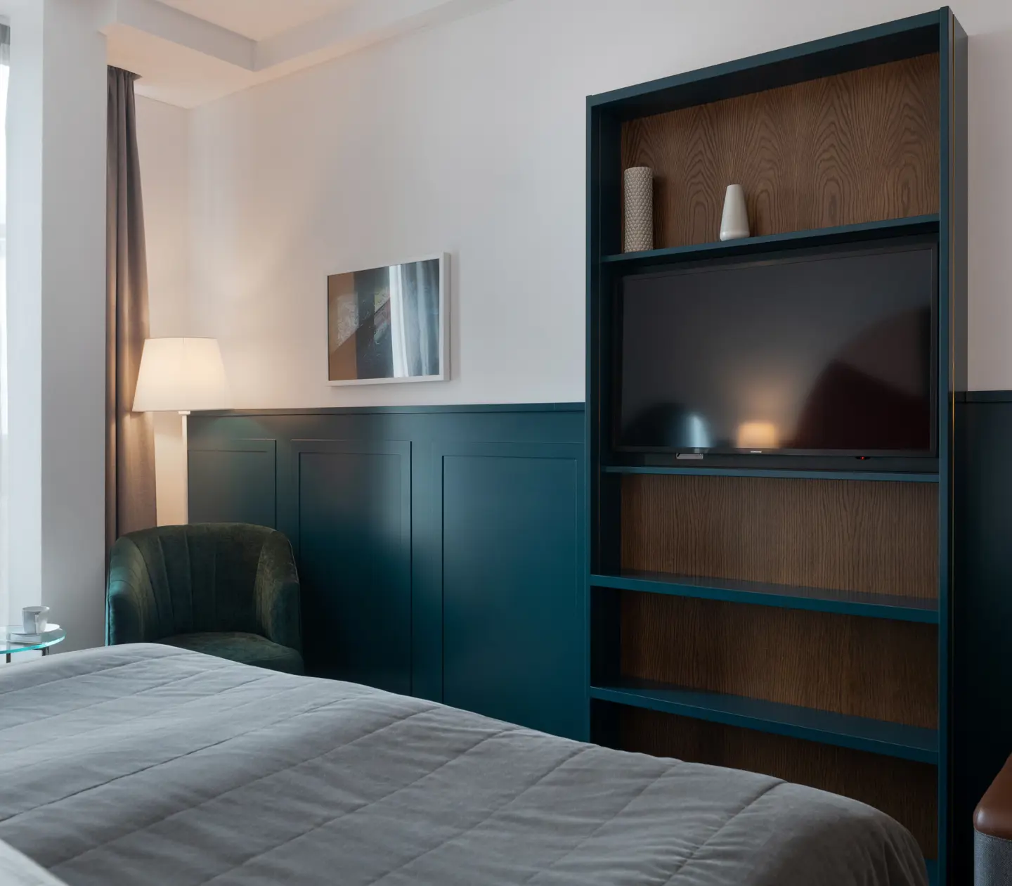 Bright hotel room with bed, large window and bookshelf