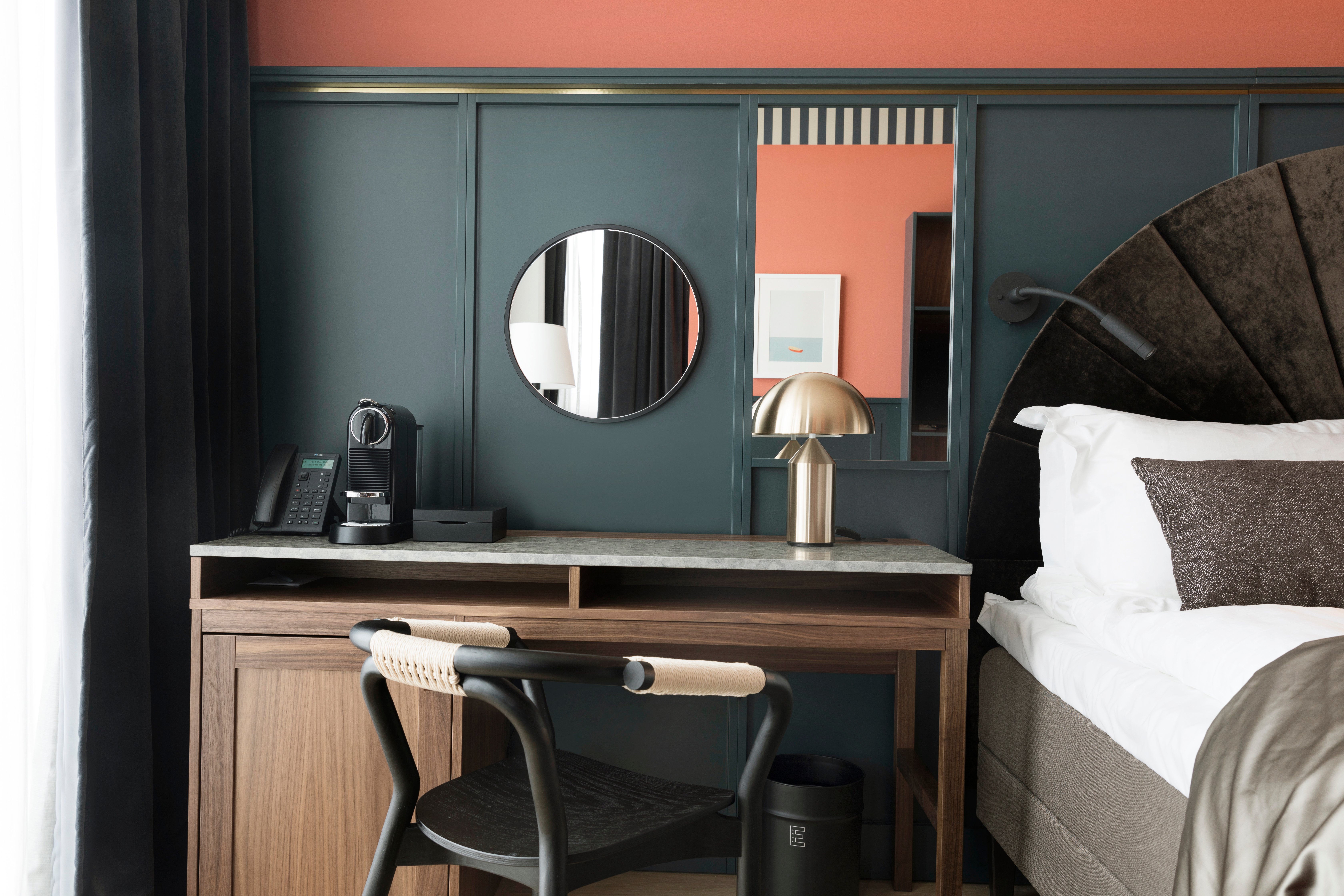 Mysigt hotellrum med säng, skrivbord, blå och röd vägg