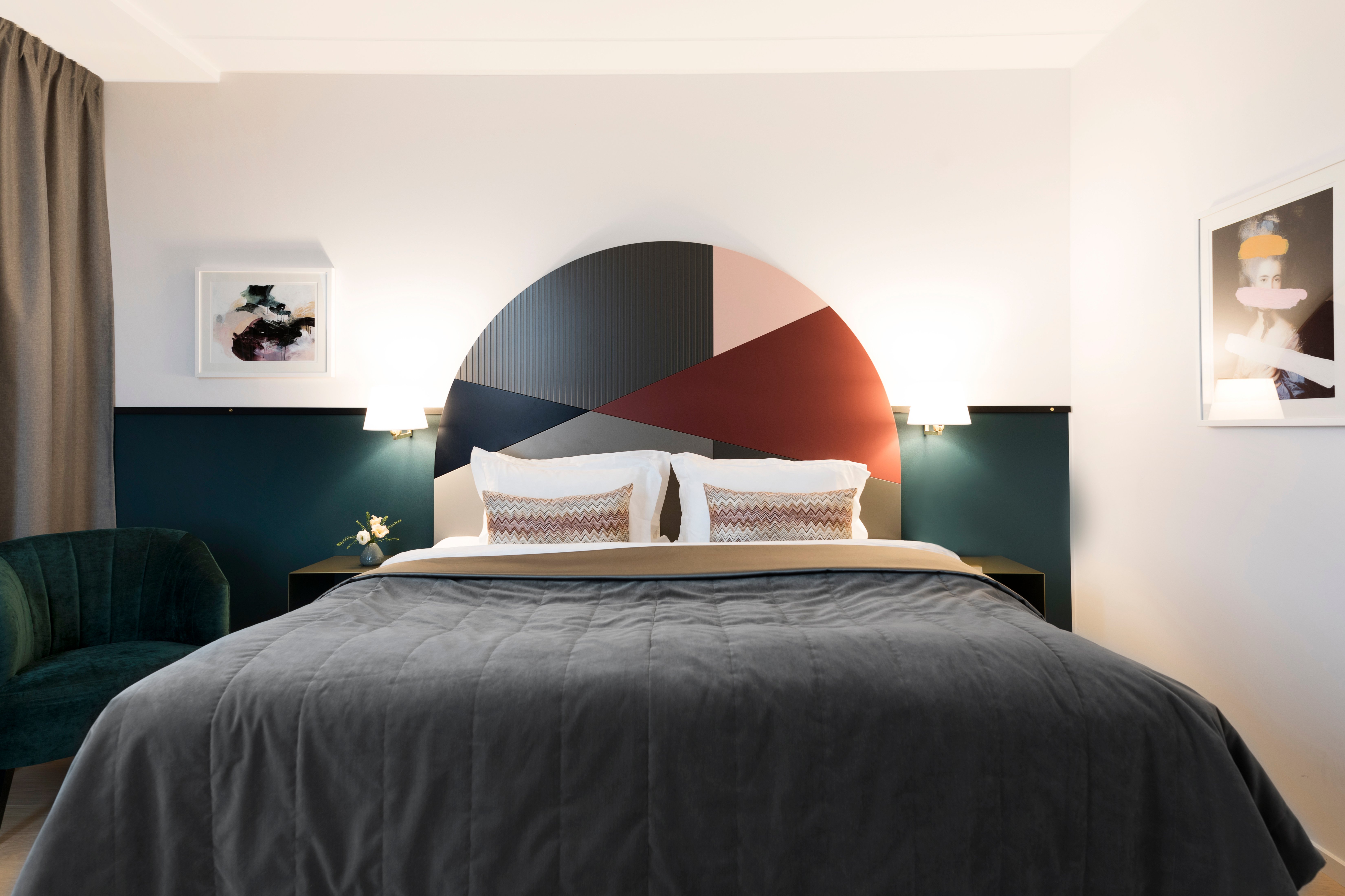 Bright hotel room with bed, colorful headboard and bedside lamps