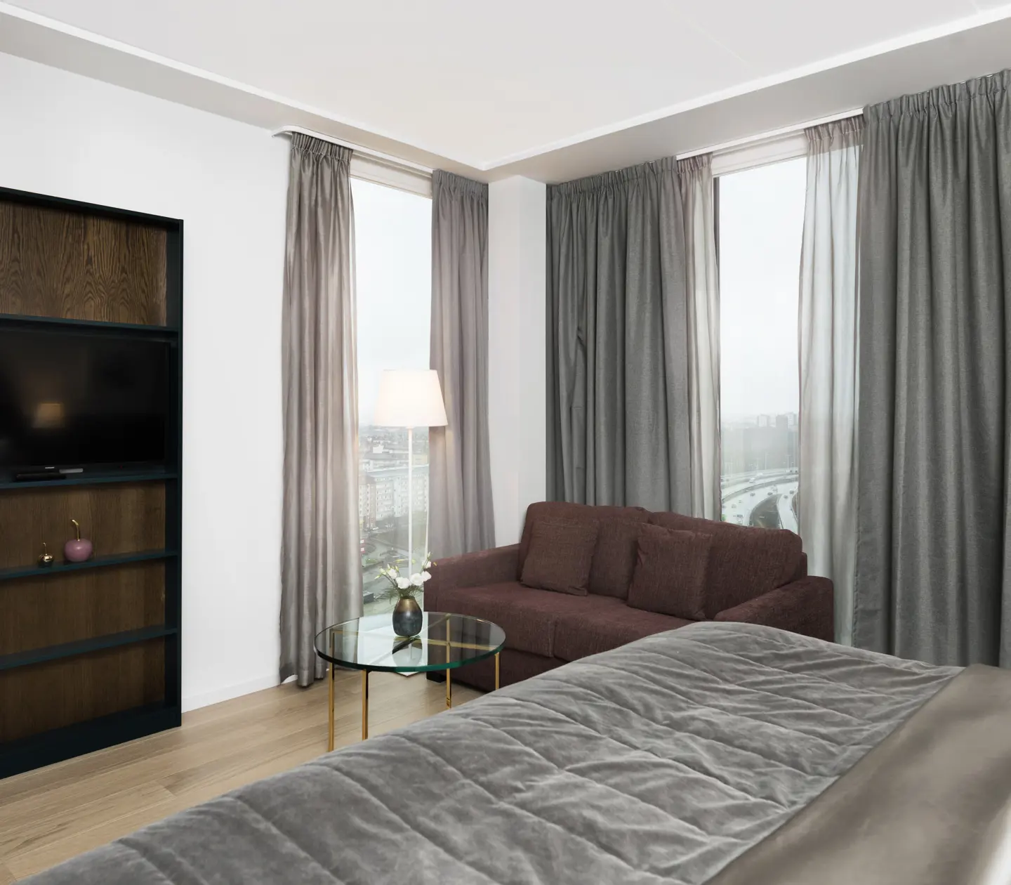Bright hotel room with bookshelf, sofa and large windows