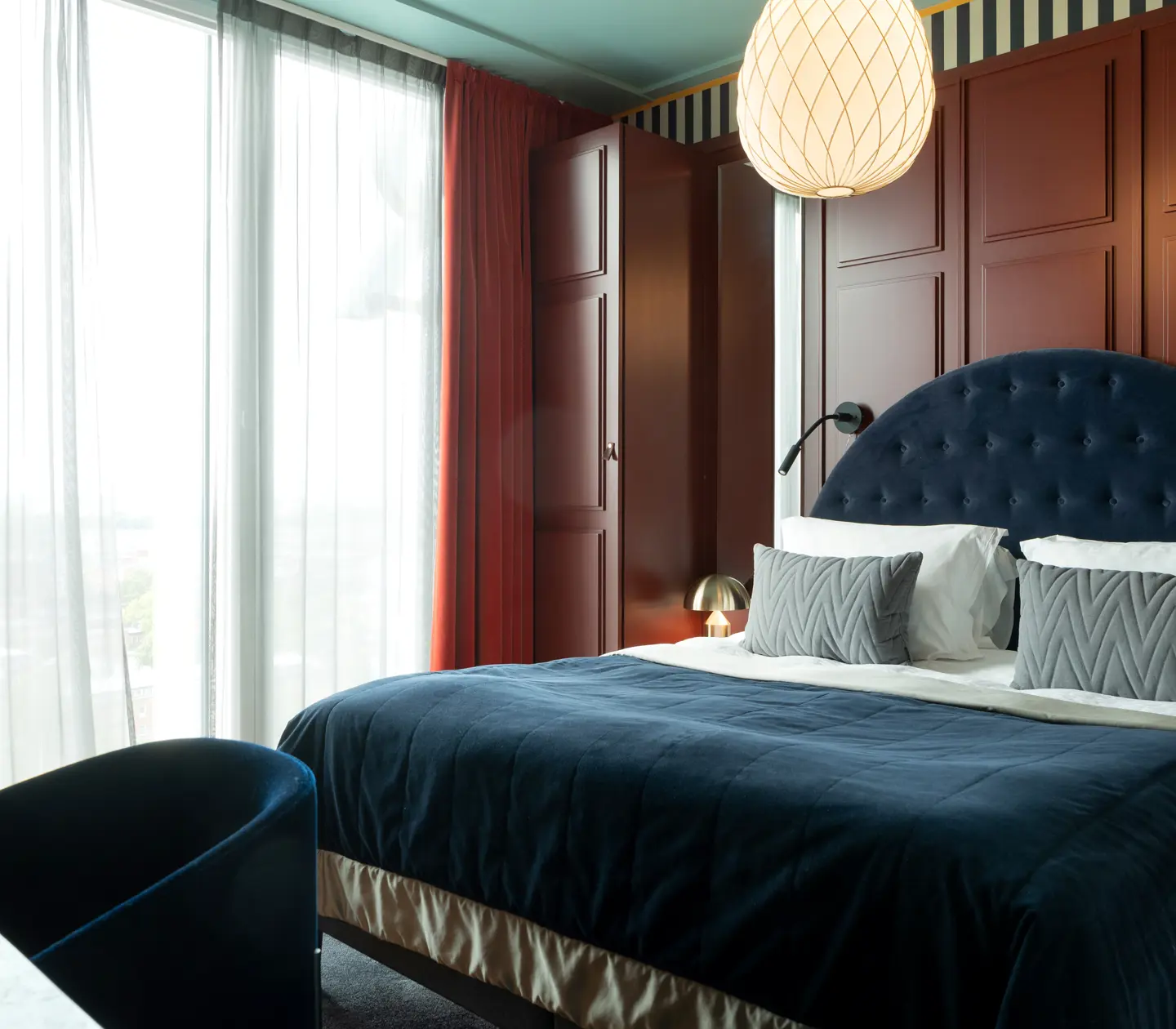 Cozy suite with dark red walls, bed and large window