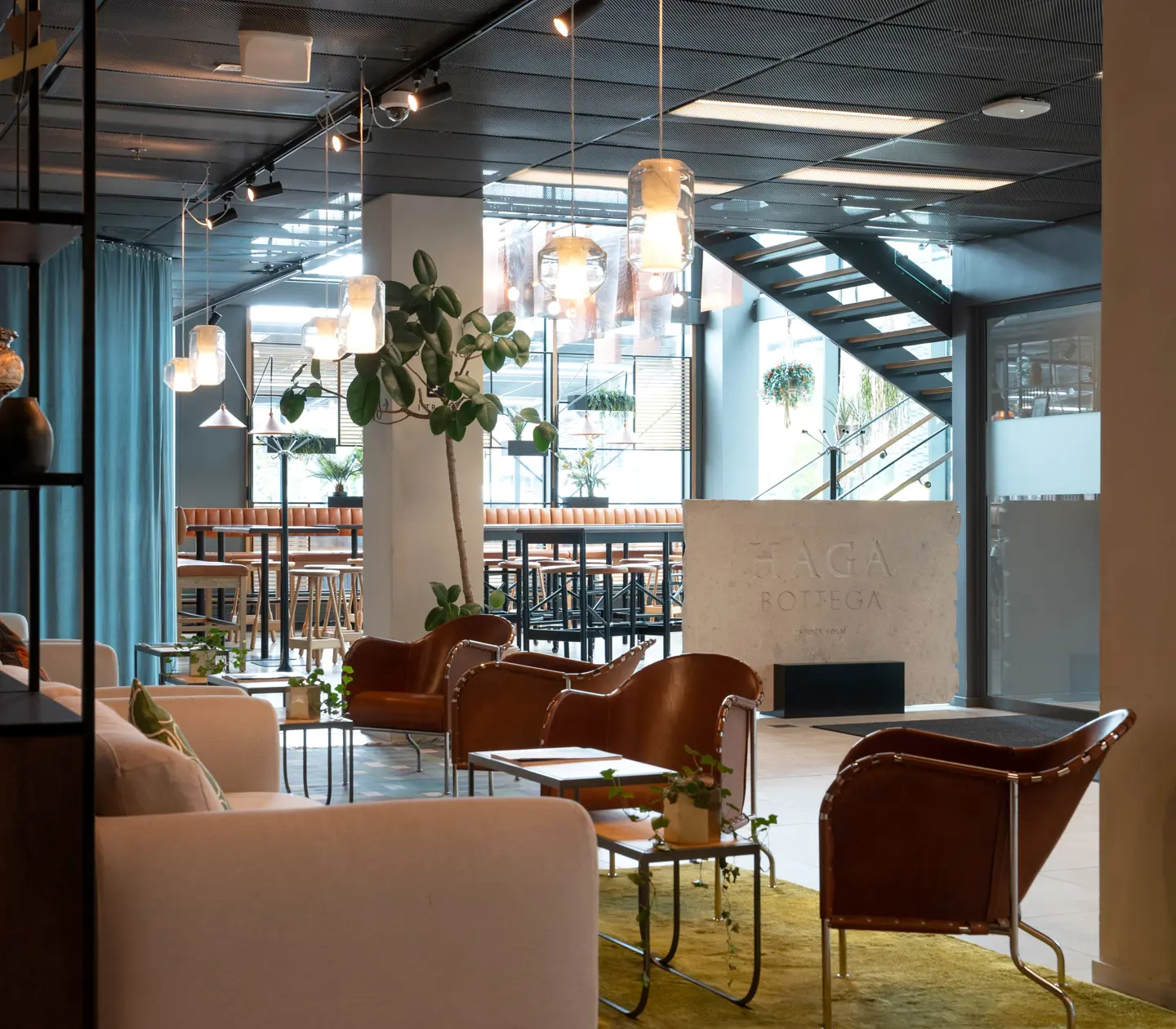 Hotel lobby with sign for "Haga Bottega", lounge furniture and plants