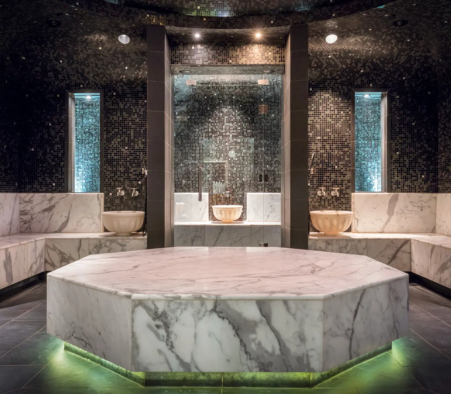 Spa environment with Turkish hammam with black tiles on the walls and white marble